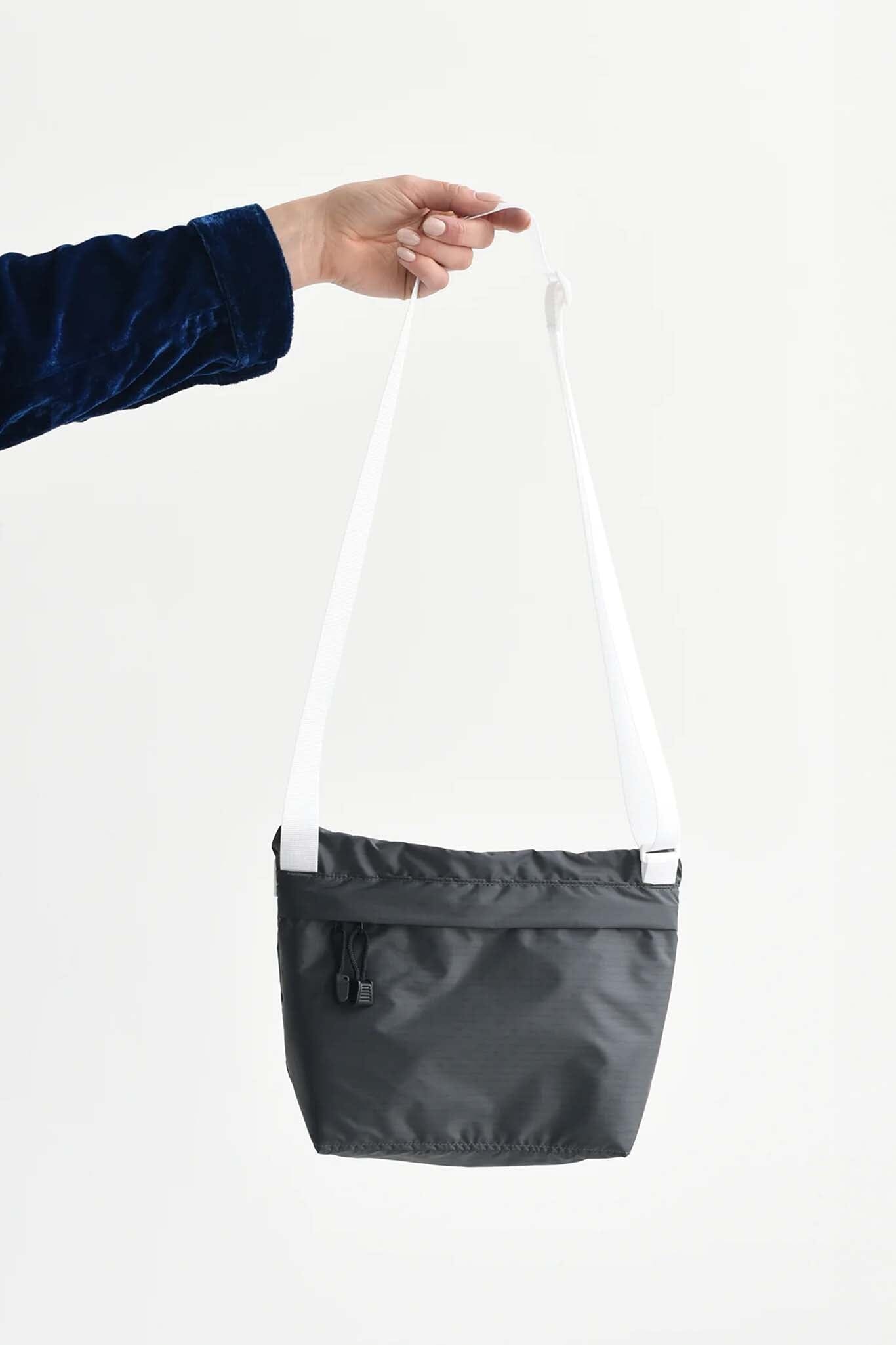 Black and white crossbody bag held by a person against a white background