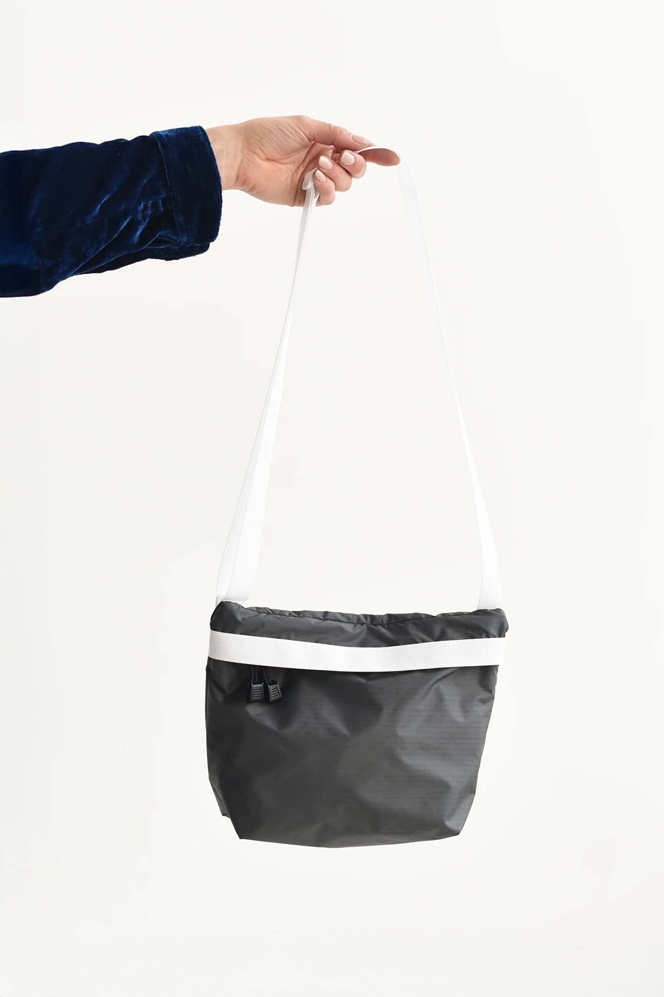 Person holding a black and white nylon zipper bag against a white background