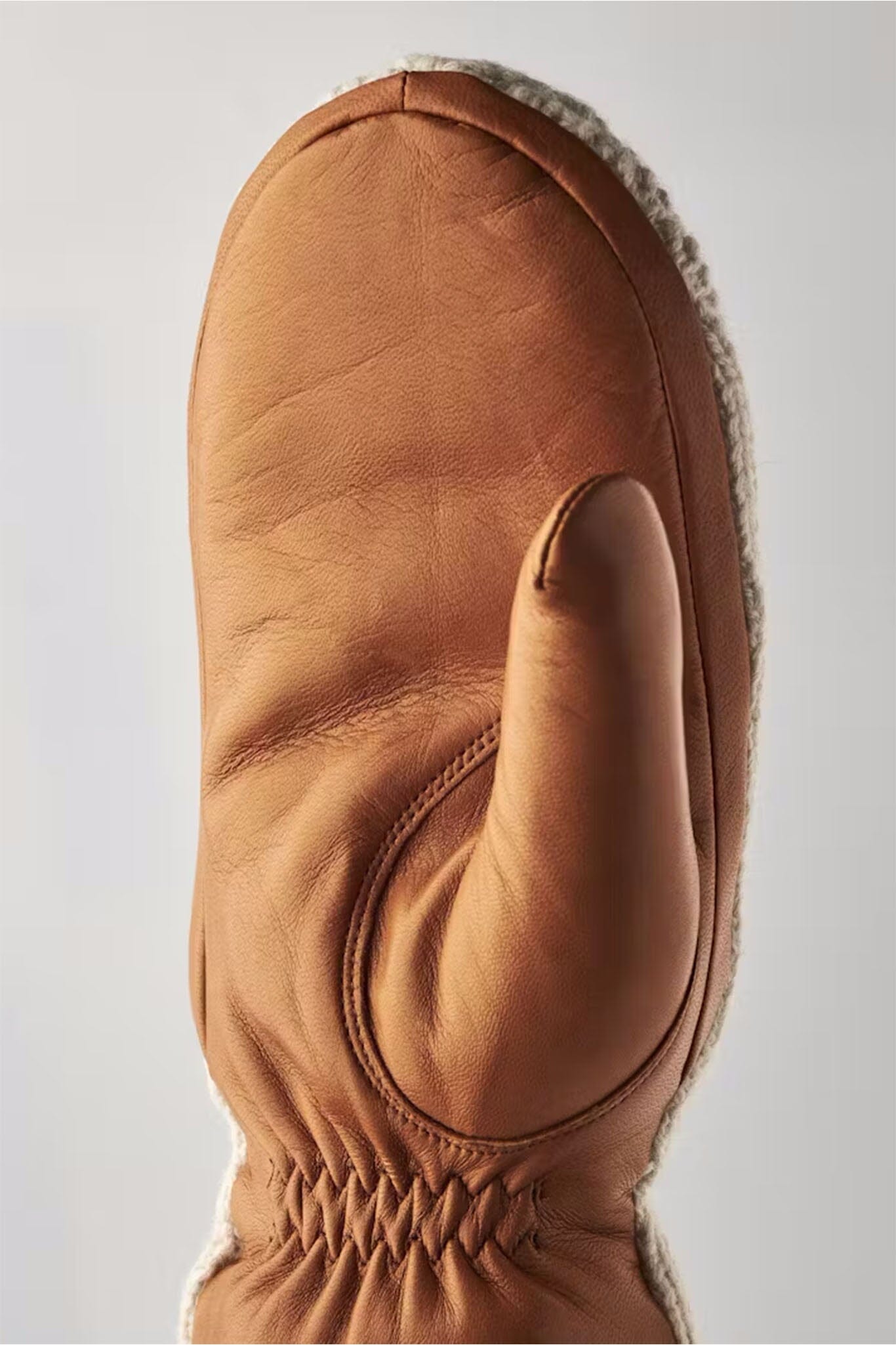 Brown leather mitten on a light gray background