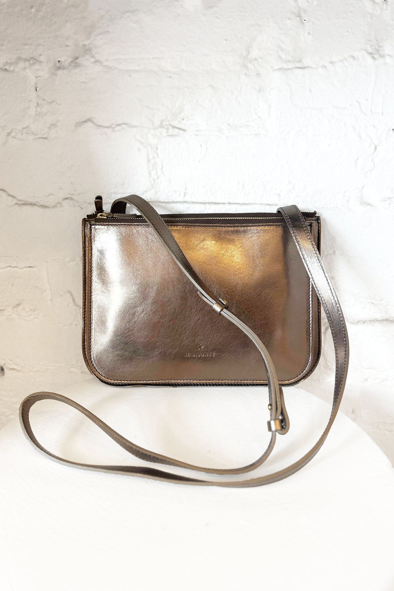 Metallic bronze crossbody bag on a light marble background