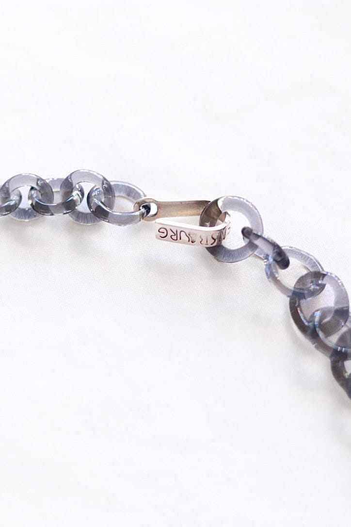 A close up of a sterling silver clasp on a grey glass chain necklace