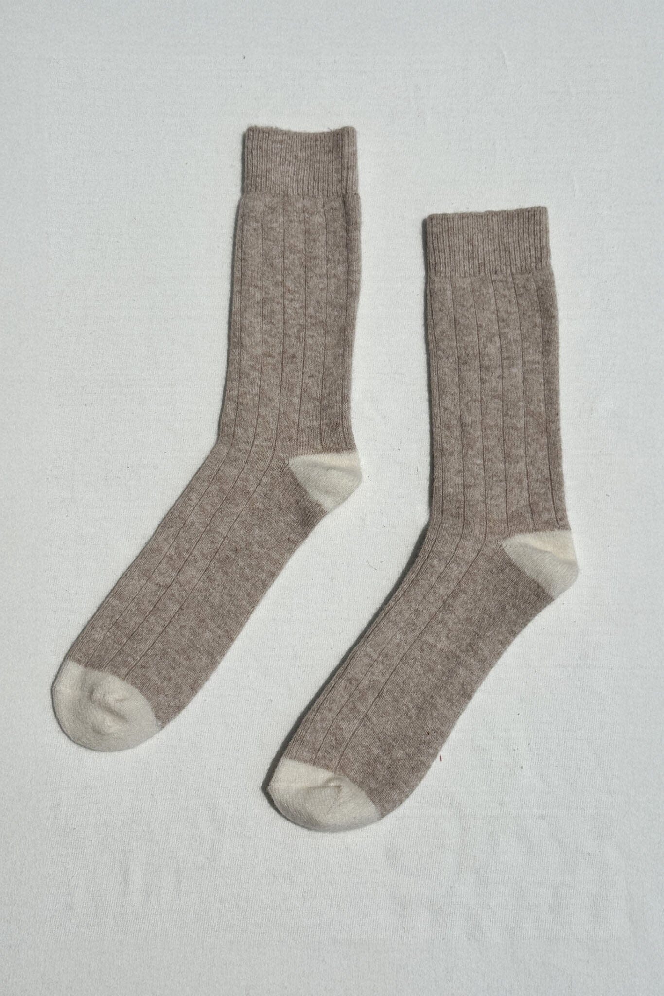 Pair of light brown and cream cashmere socks on a light gray background