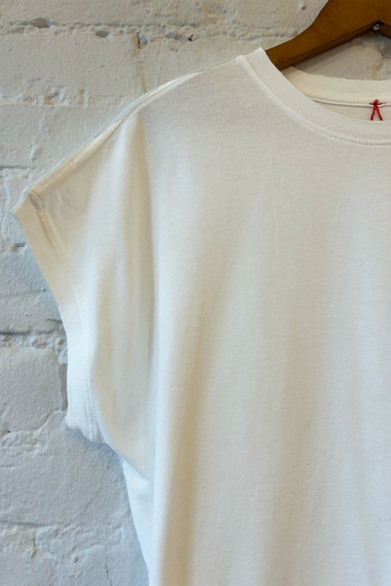 Close up of a white t-shirt on a hanger against a textured wall