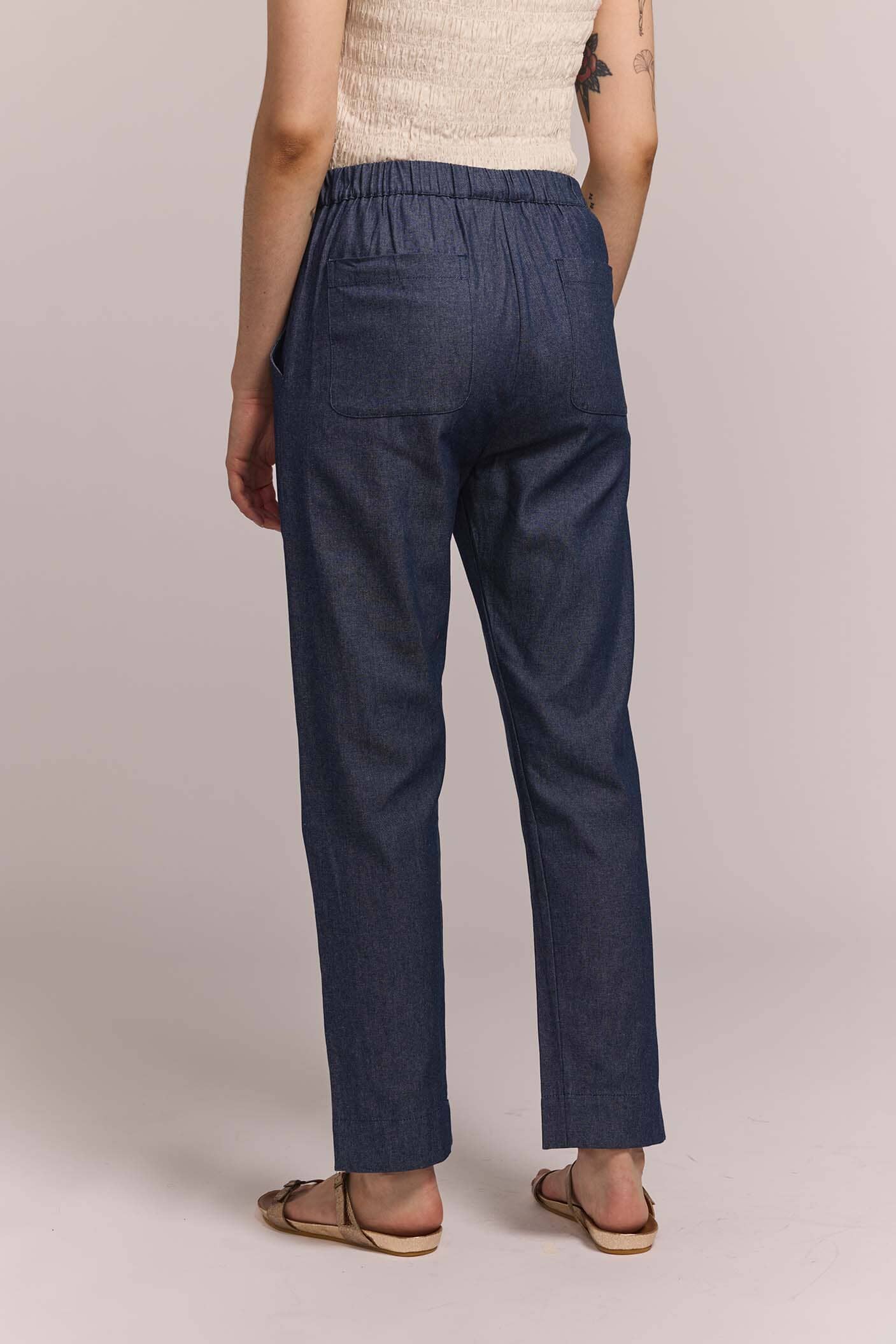 The back view of a person wearing navy blue pants on a plain background