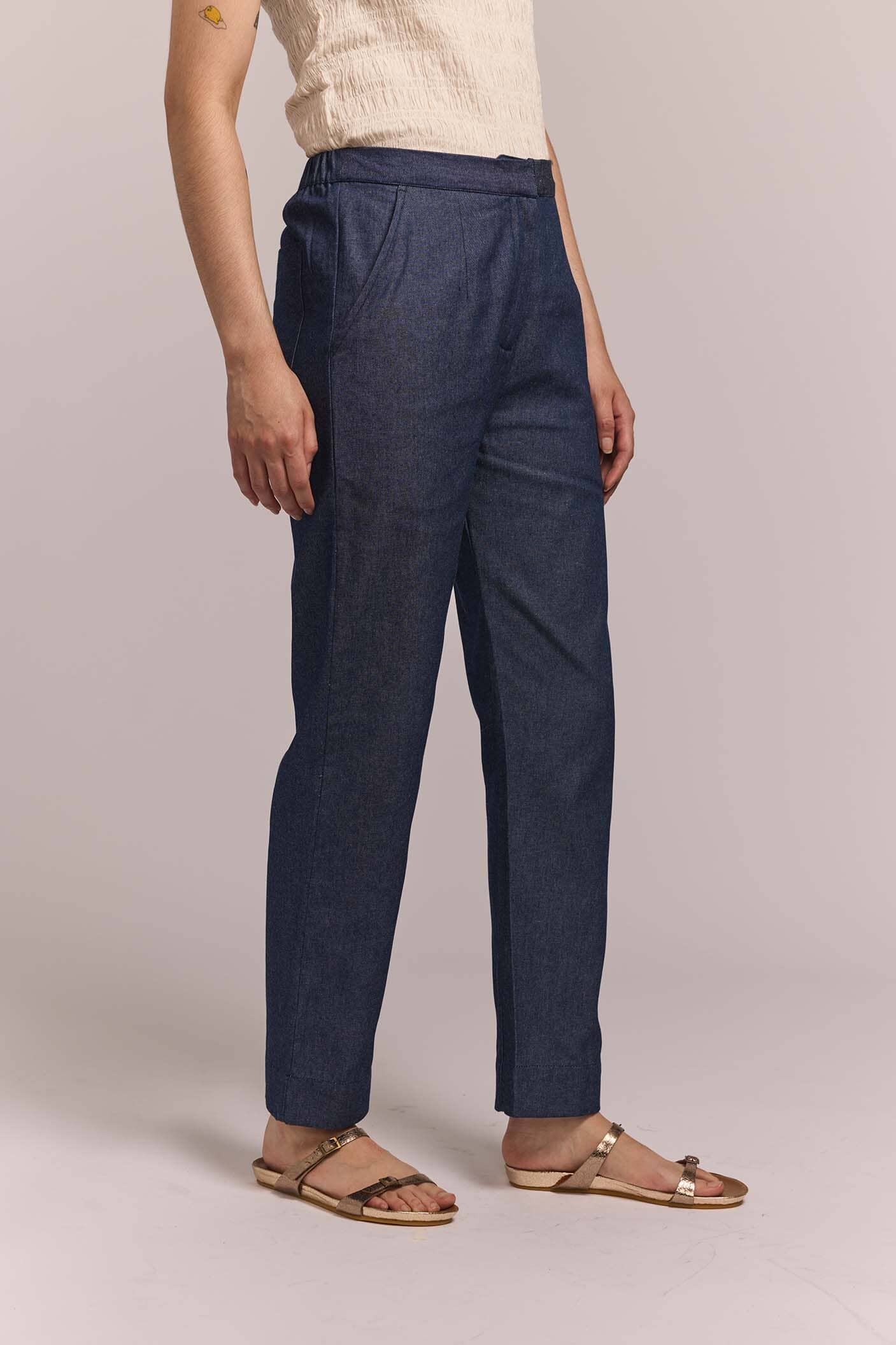 Person wearing navy blue straight leg pants on a plain background