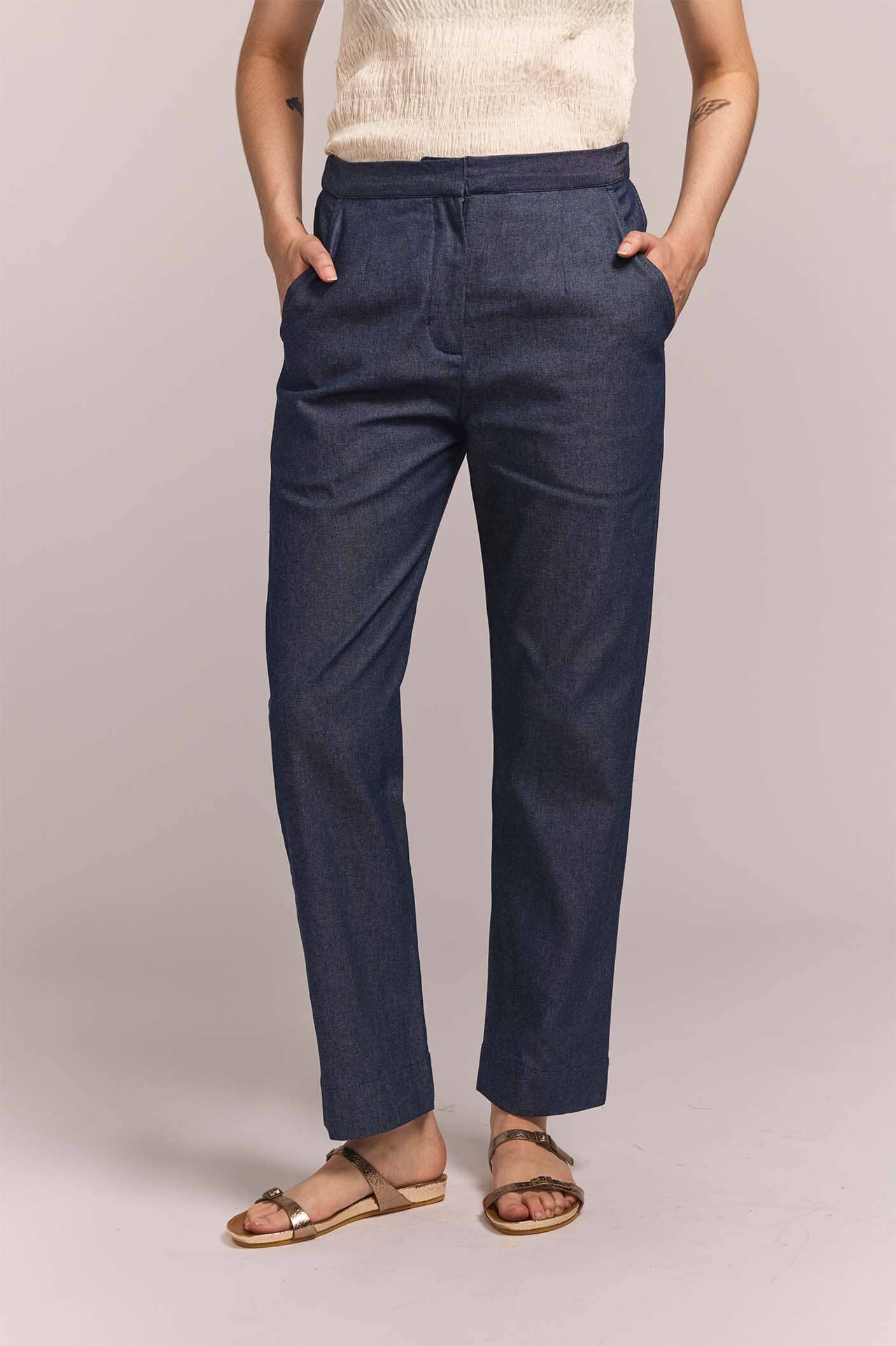 Person wearing navy straight leg pants with a plain background