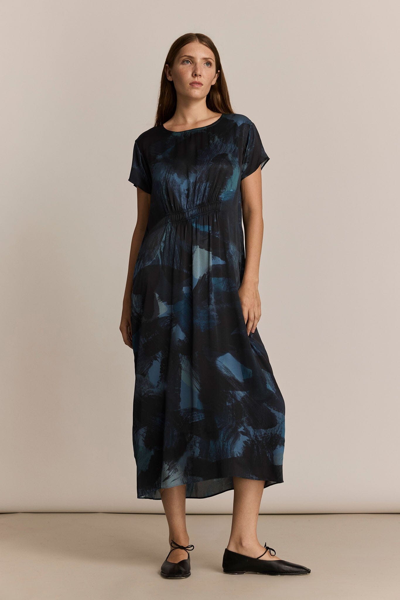 Woman wearing a dark blue patterned dress against a beige background