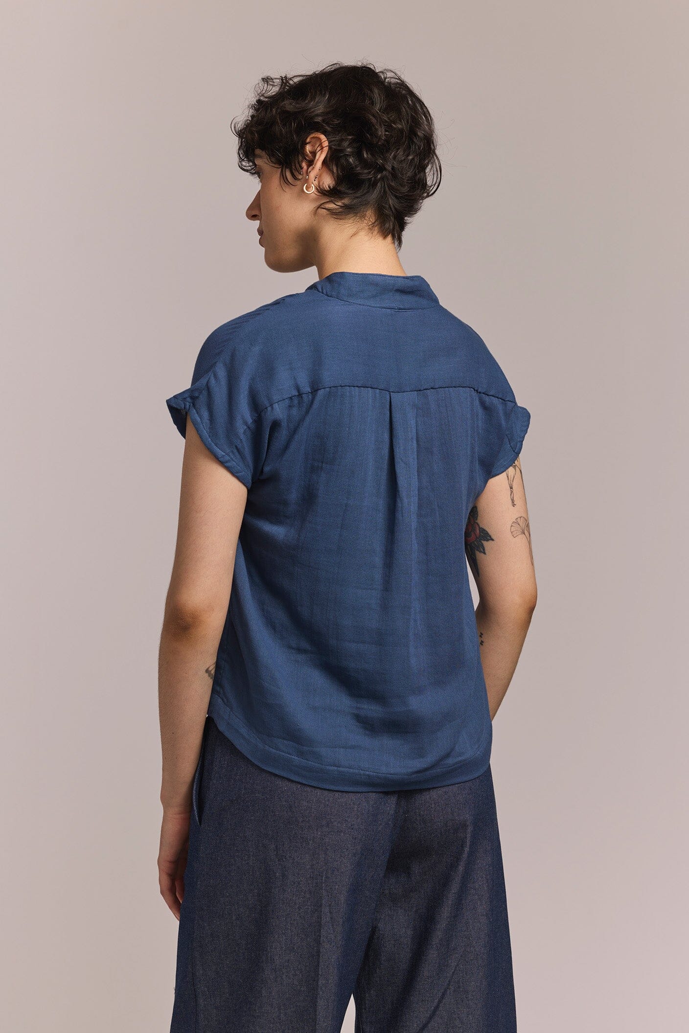 Person wearing a blue shirt and pants against a plain background