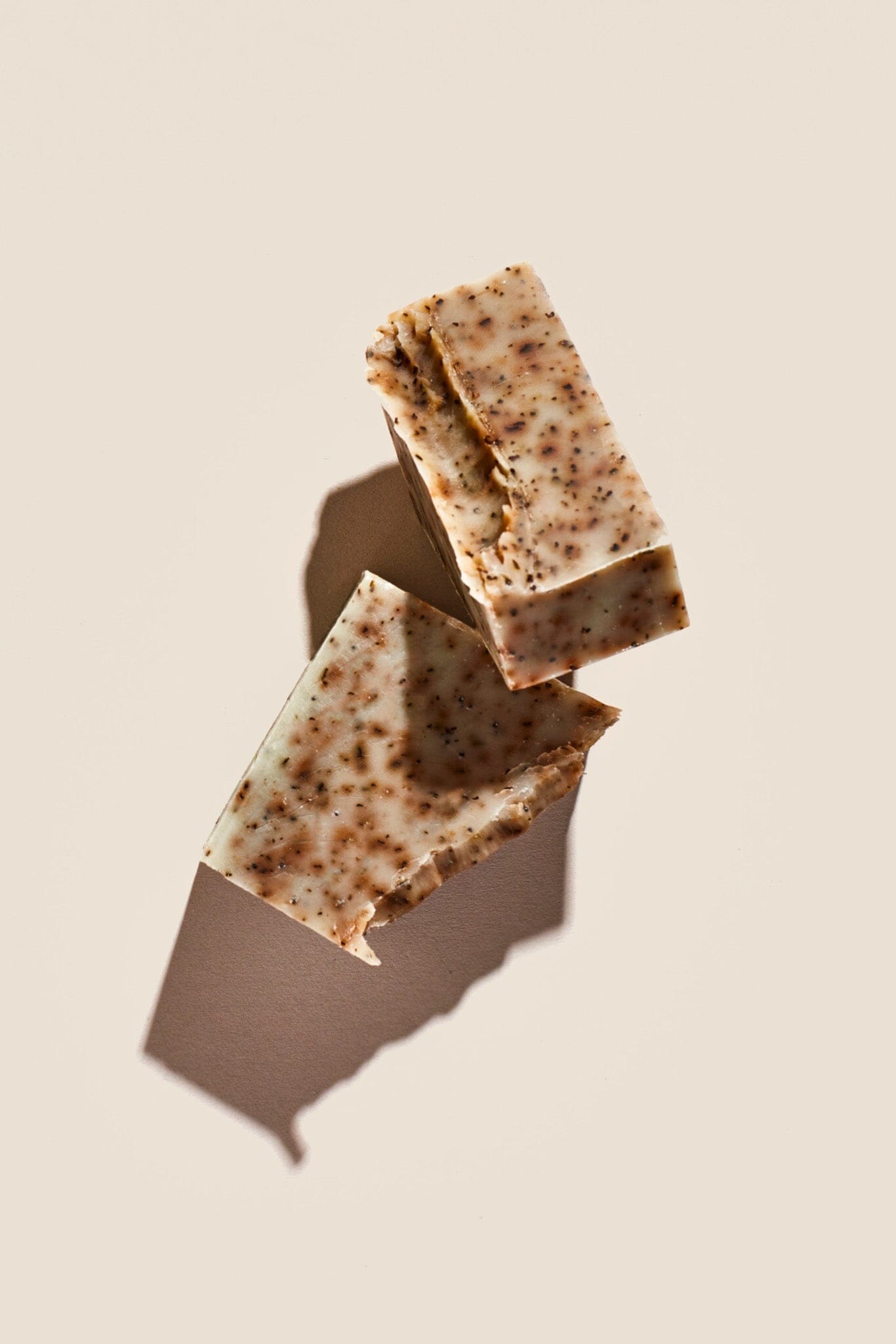 Two bars of soap with a speckled green and brown appearance, placed on a neutral background.