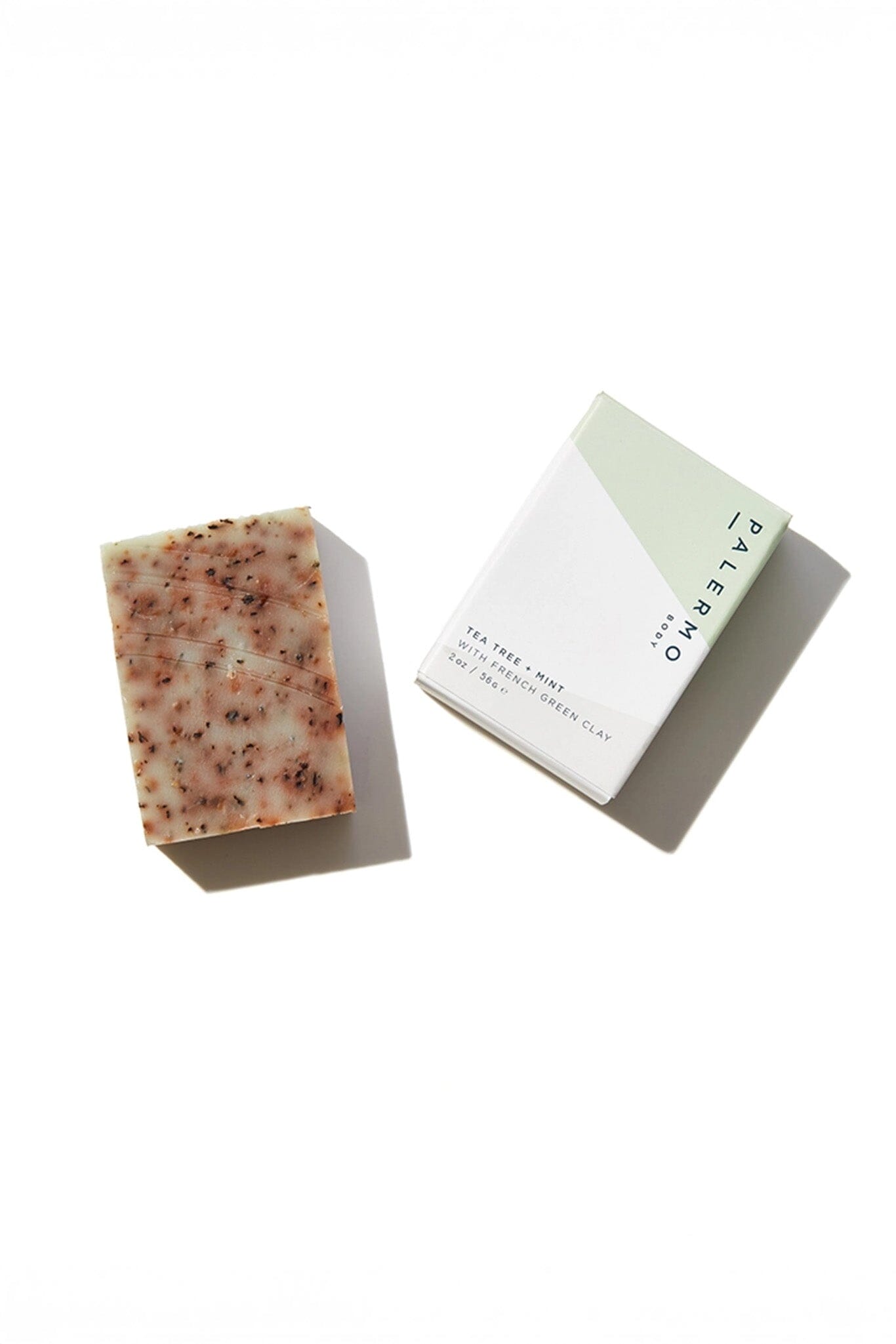 A bar of soap with a textured surface next to its packaging, which is a simple white card with 'Palermo Body' written on it.