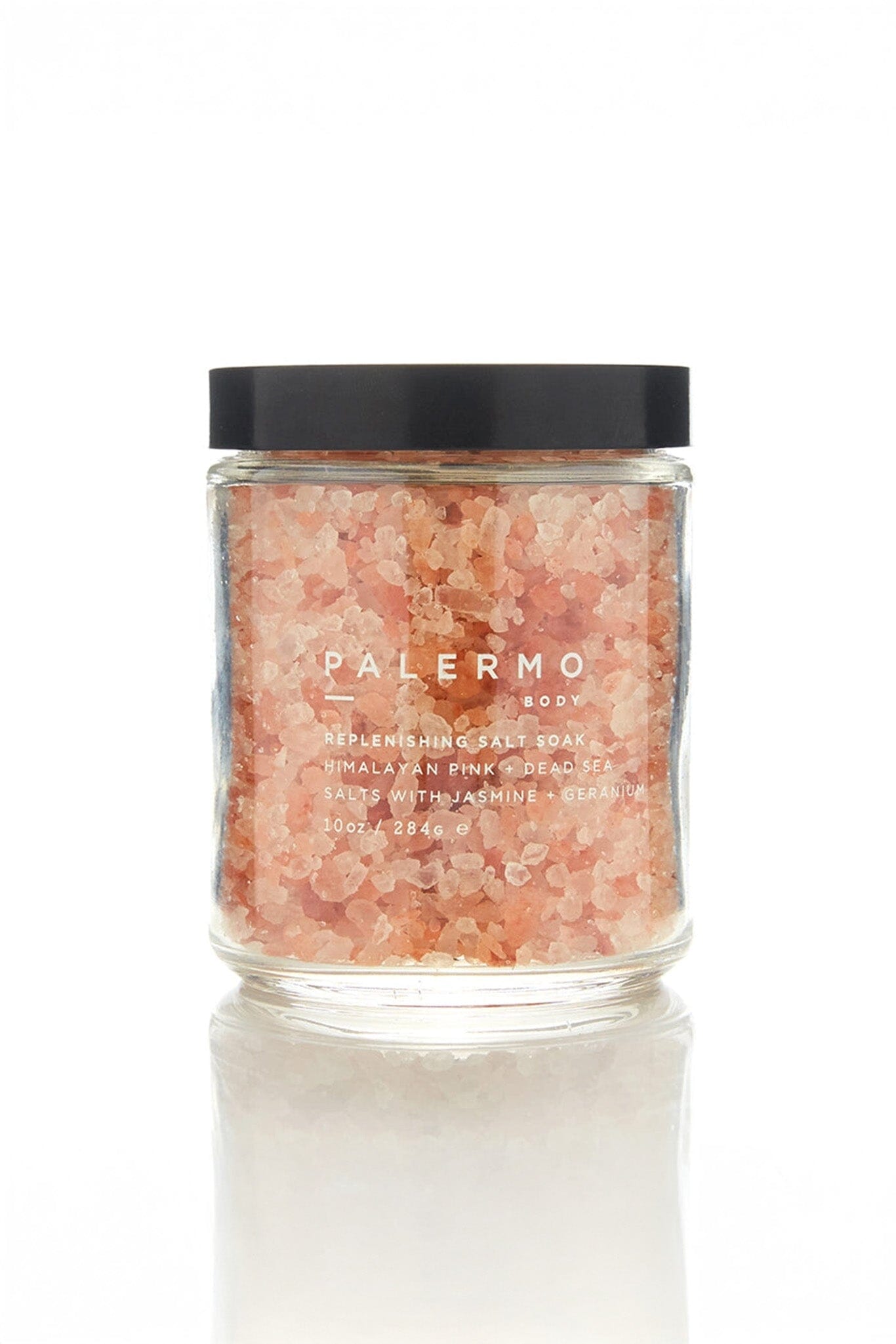 A clear glass jar filled with pink Himalayan salt, with a black lid and a label that reads 'PALERMO BODY HIMALAYAN PINK SALT SOAK'.
