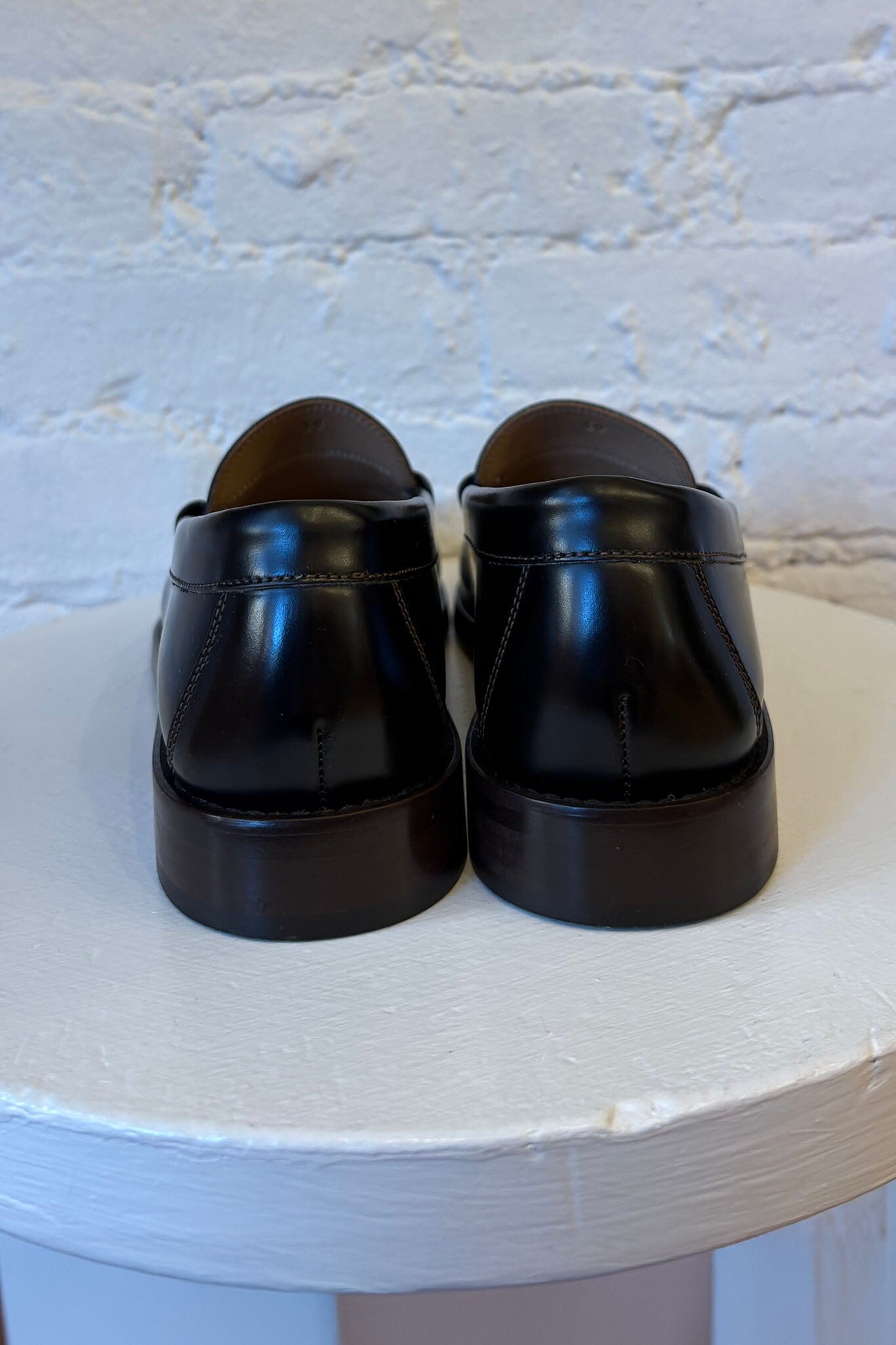 Pair of black loafers on a white surface with a light blue textured background