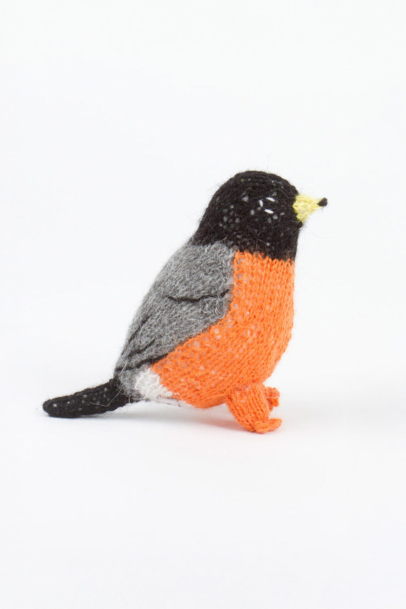 Knitted toy resembling robin with orange, black, and gray colors on a white background