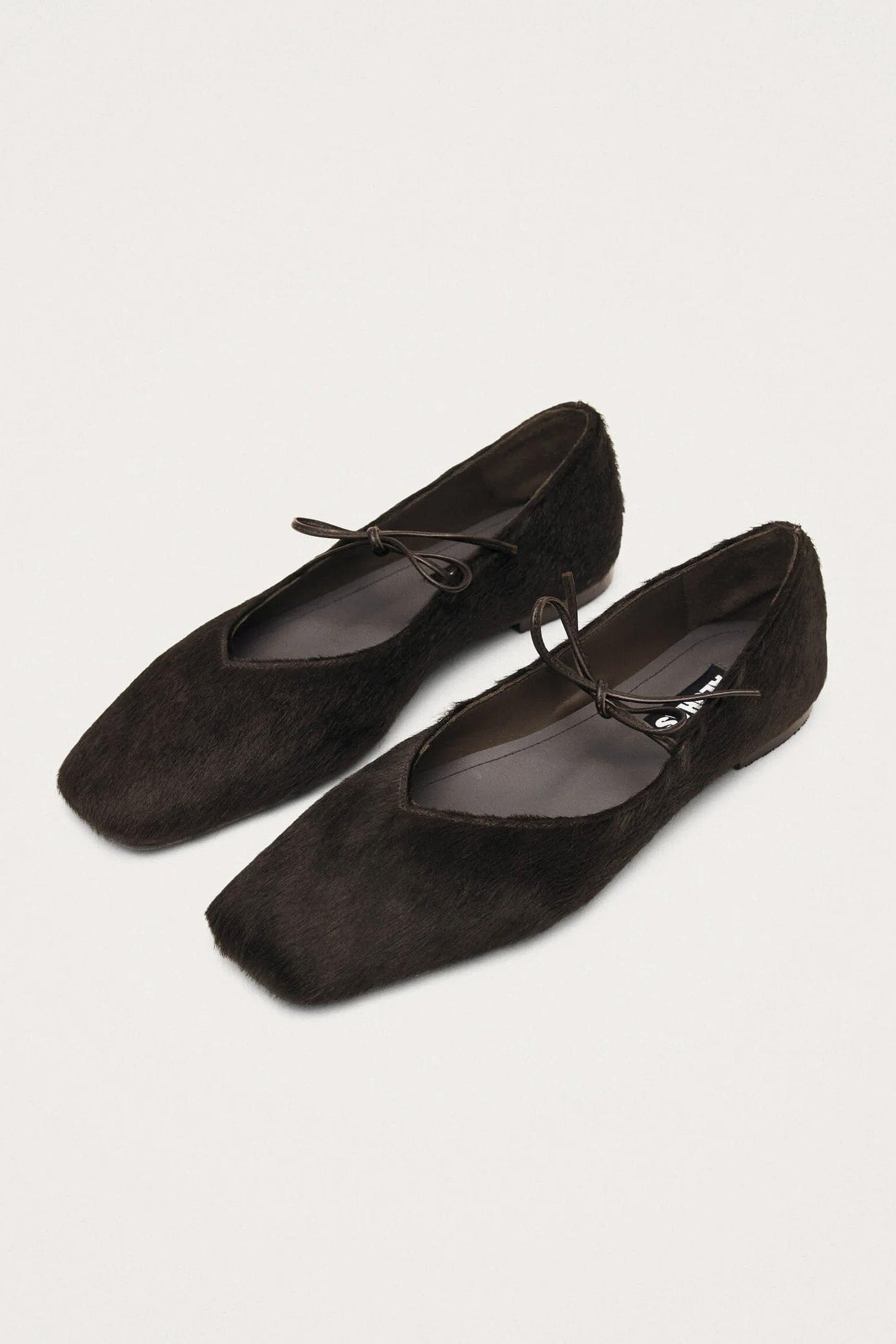 A pair of soft brown leather ballet flats with square toes and a bow detail.
