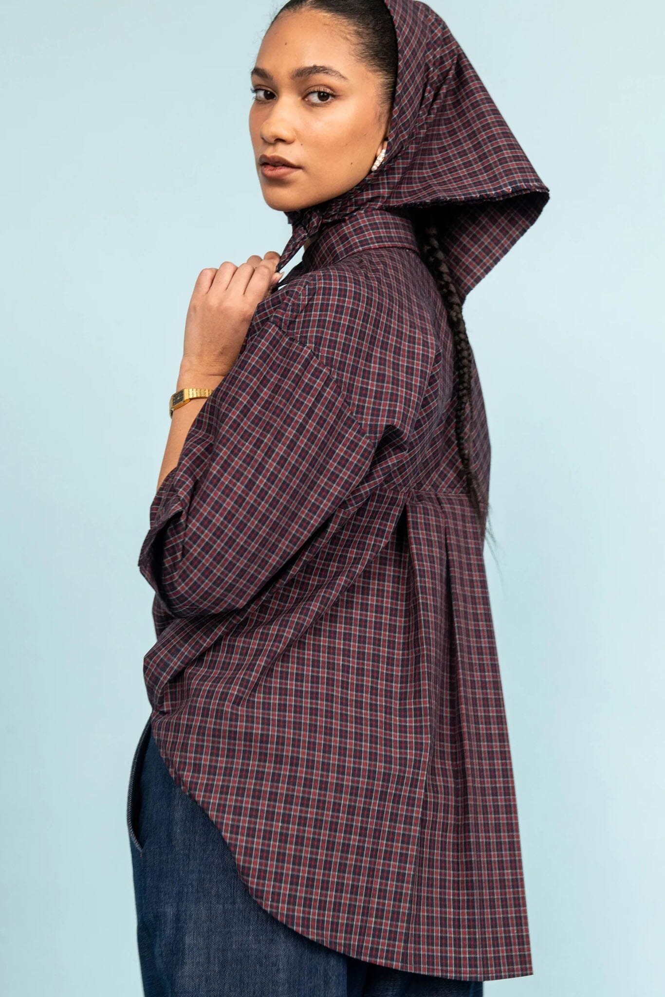 Person wearing a plaid shirt and scarf against a light blue background