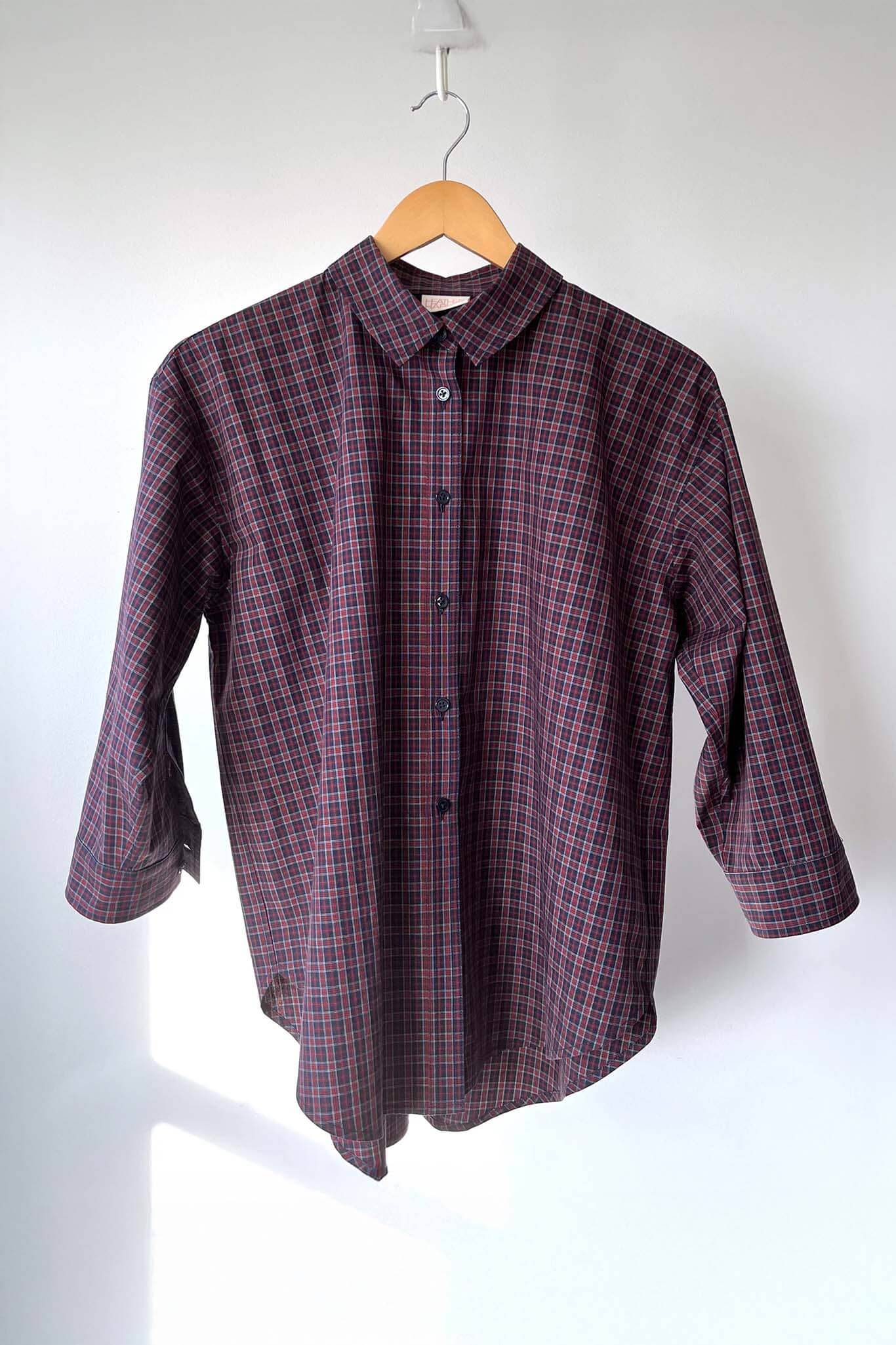 Plaid shirt on a hanger against a white background
