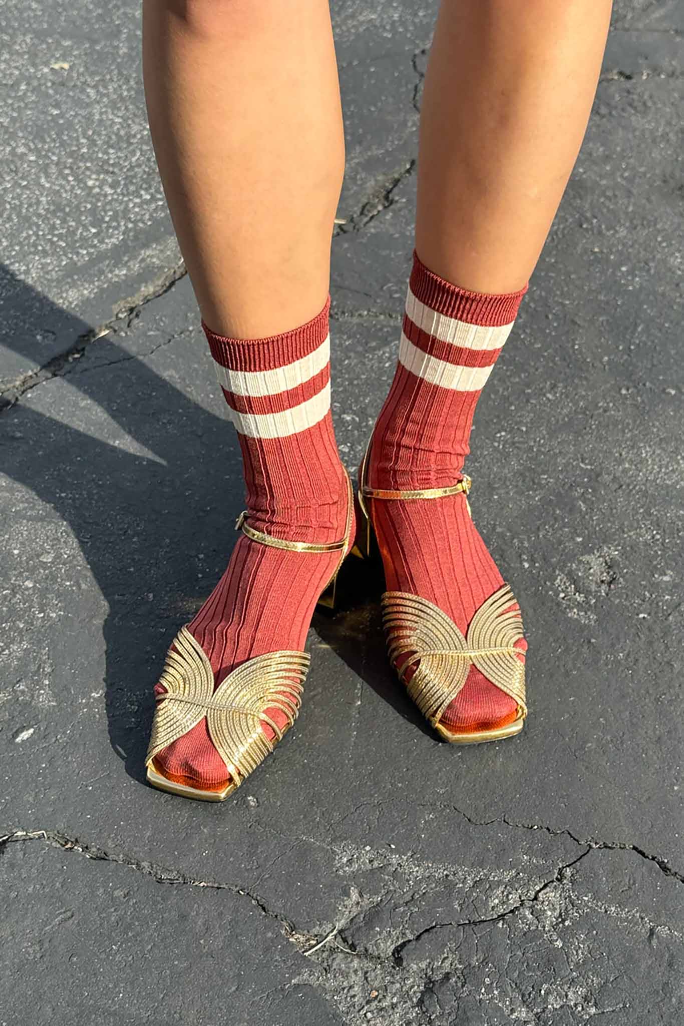 A pair of red and white striped socks worn with open-toe flat sandals.
