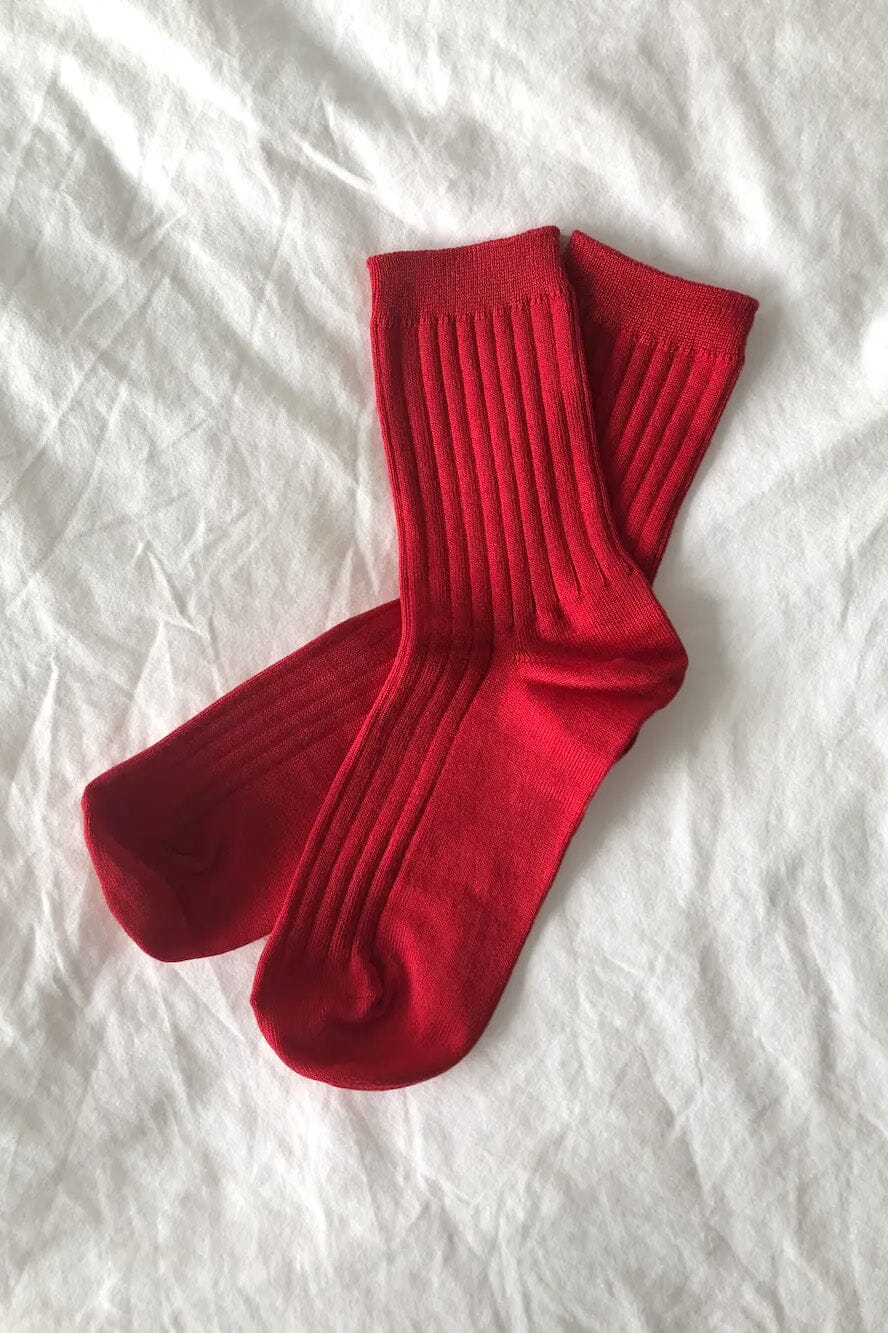 Pair of ribbed red crew socks on a white textured surface