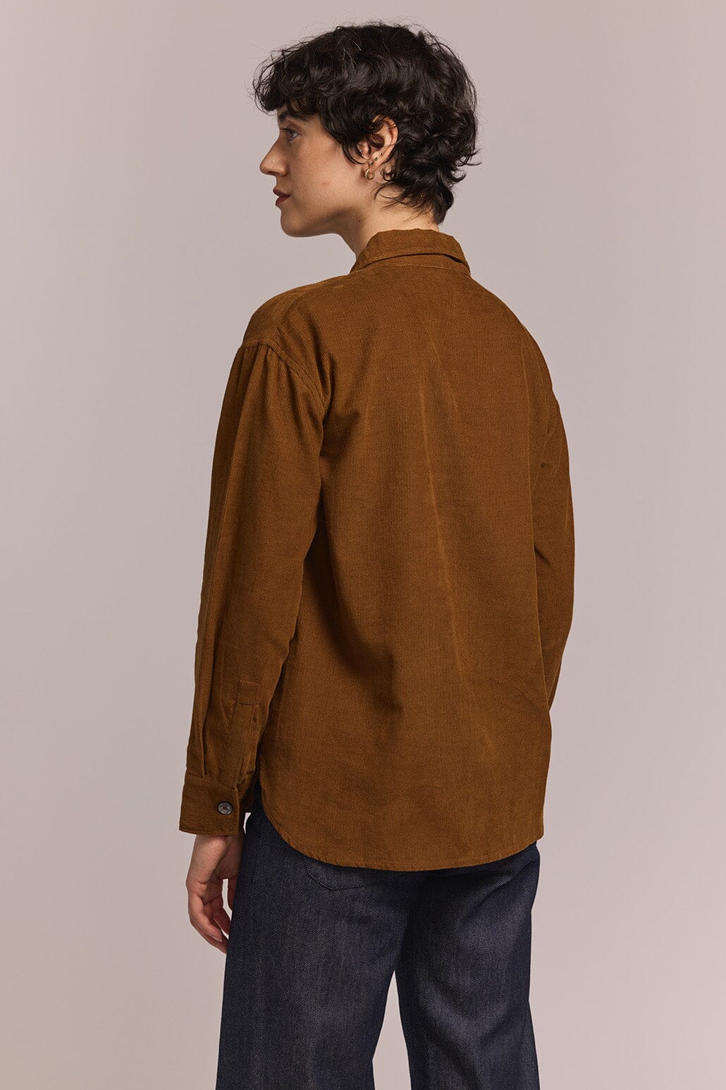 Person wearing a brown corduroy shirt against a plain background