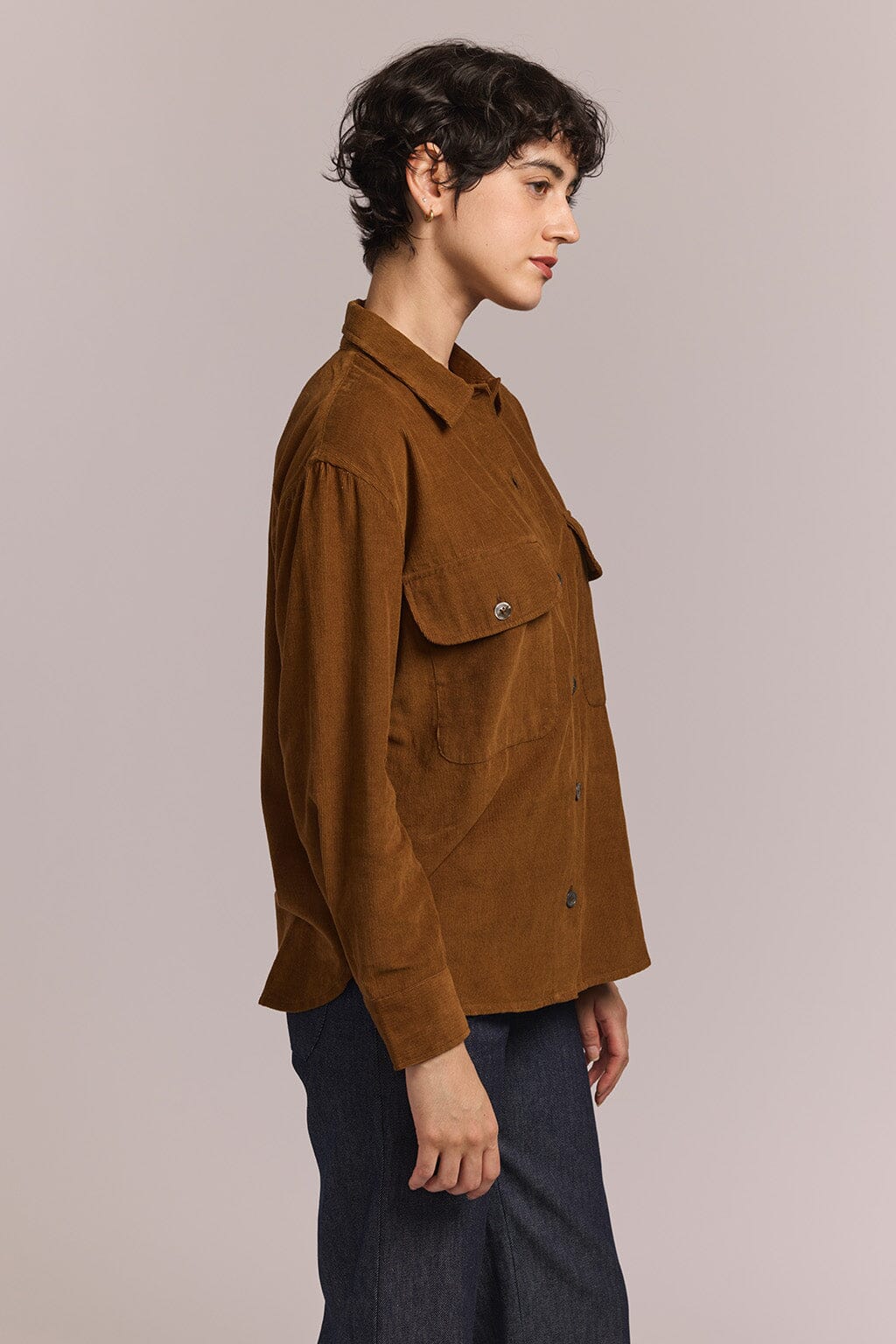 Person wearing a brown jacket against a plain background