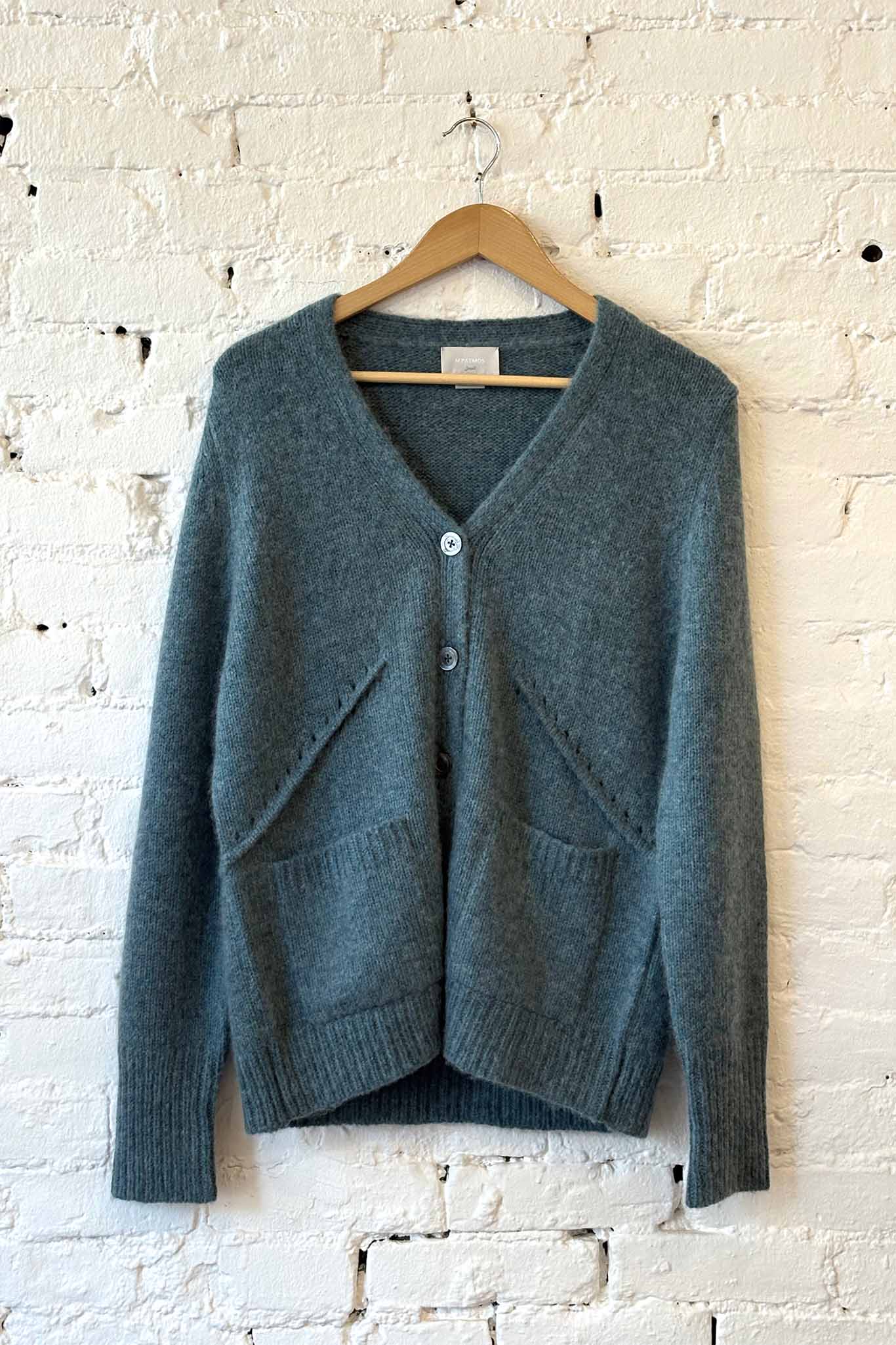 Green long sleeve wool v-neck cardigan on a white brick wall