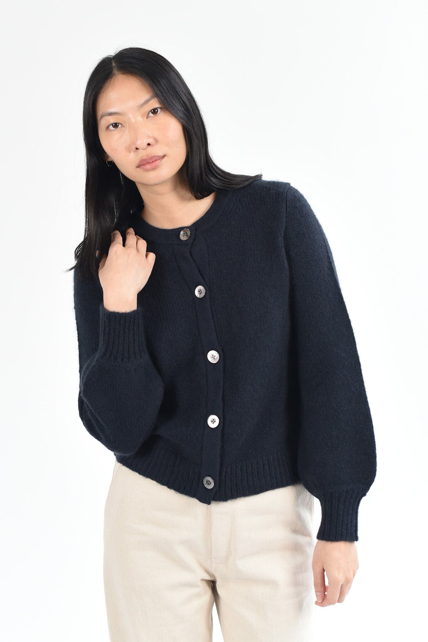 Woman wearing a black merino wool long sleeve cardigan against a white background.