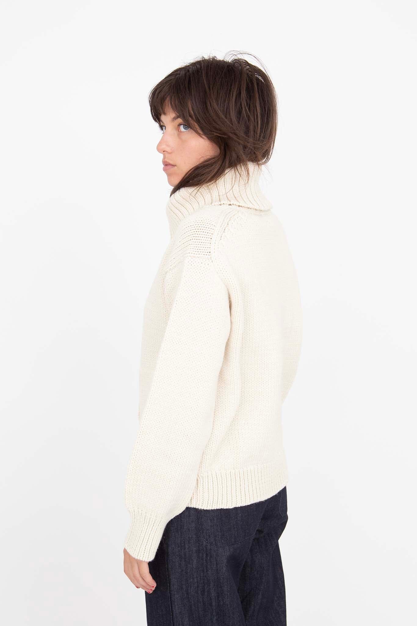 The side view of a white knit longsleeve sweater.