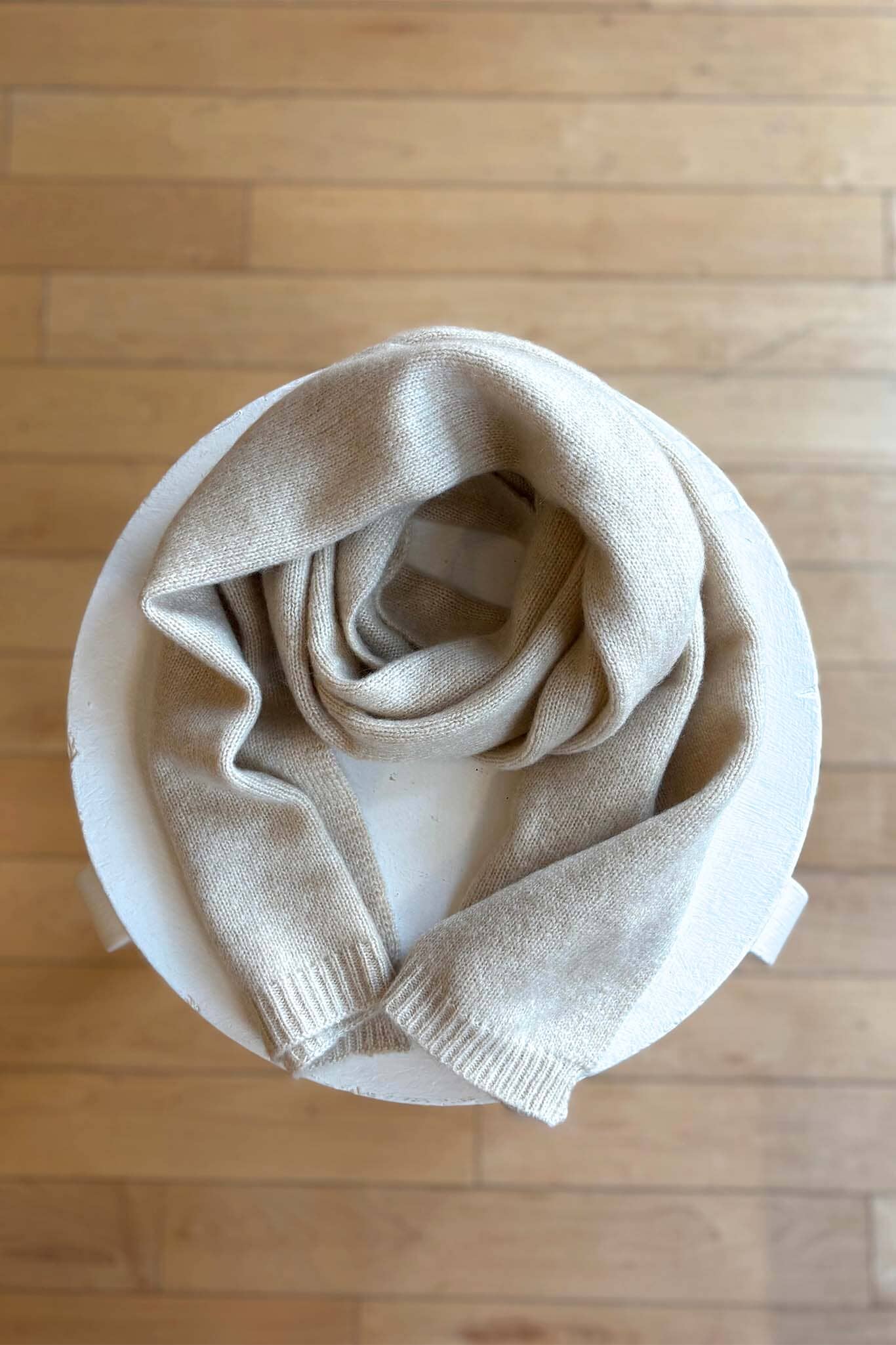 Beige scarf on a white plate with a wooden background