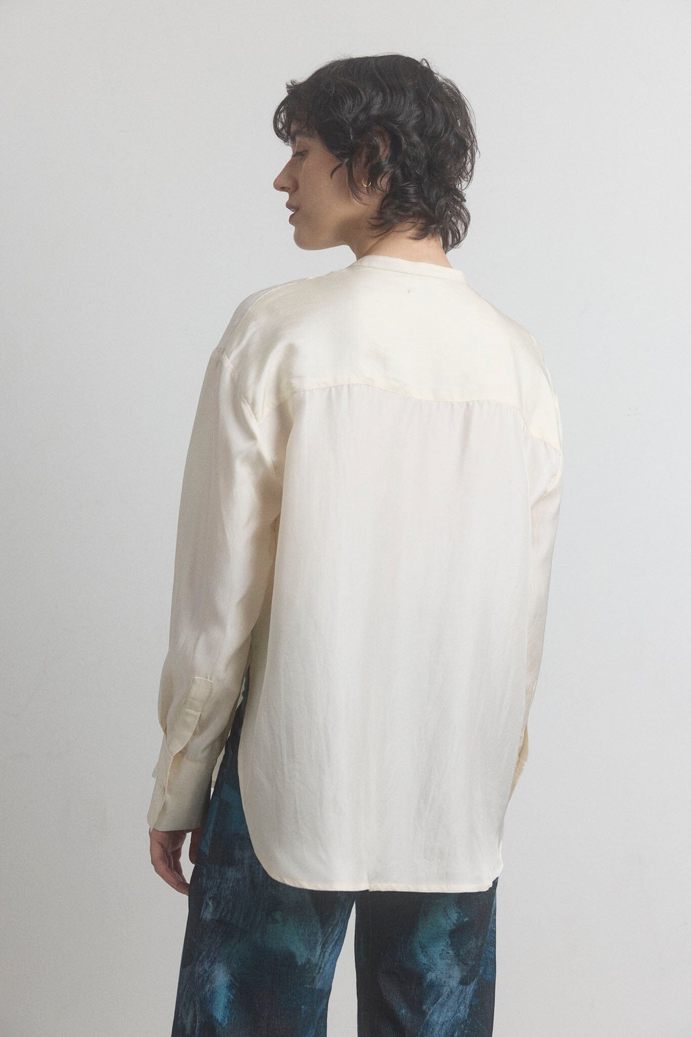 Woman facing the back wearing a beige cotton long-sleeve M.PATMOS shirt against a plain background