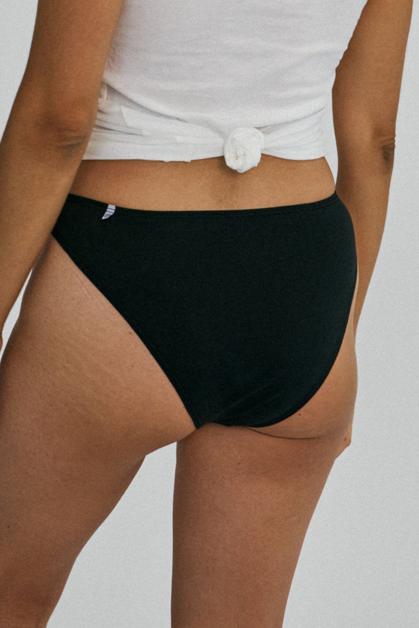 A woman wears black mid rise french cut underwear