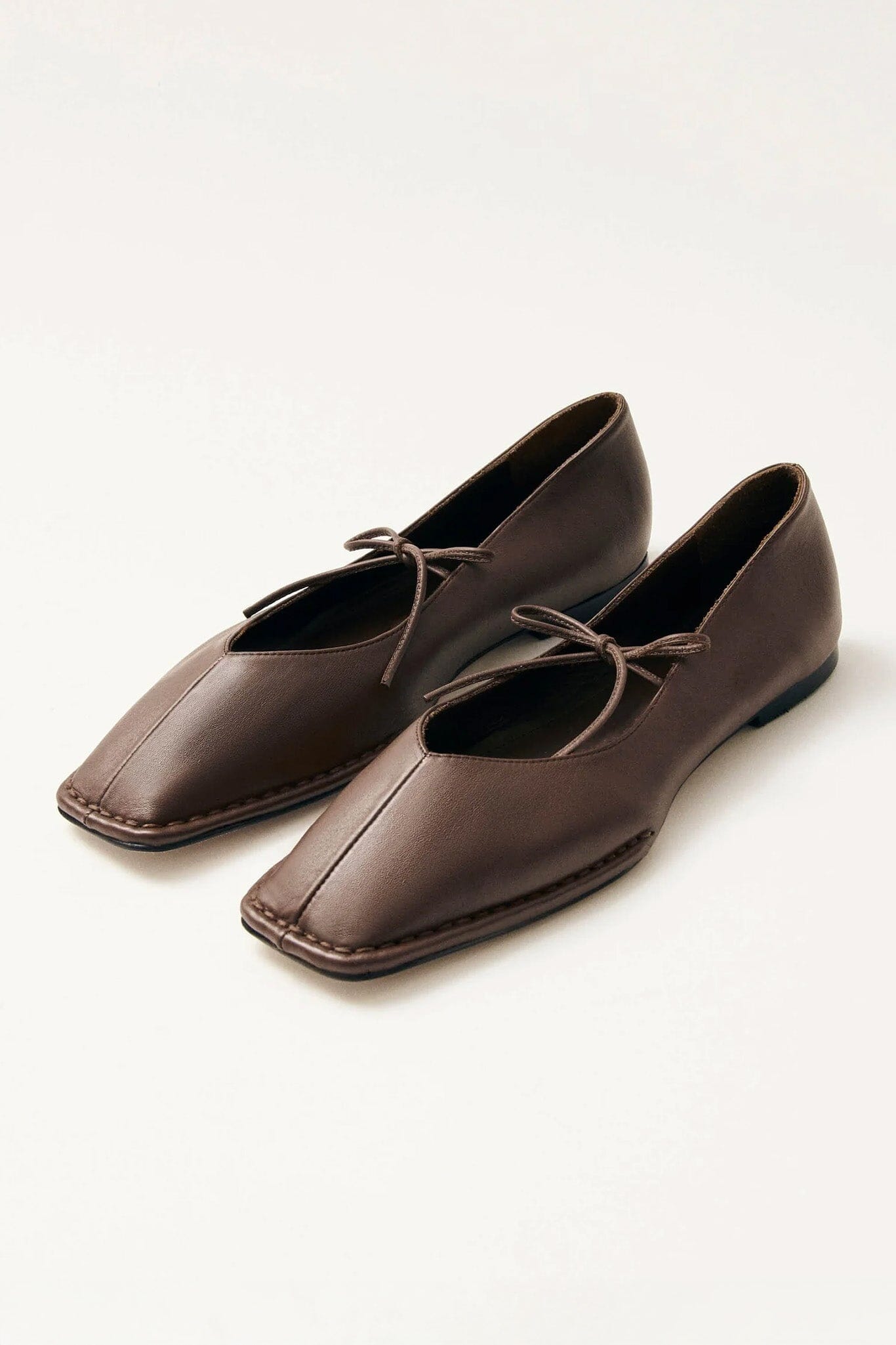 Pair of brown square toe leather flat shoes with a top tie on a white background