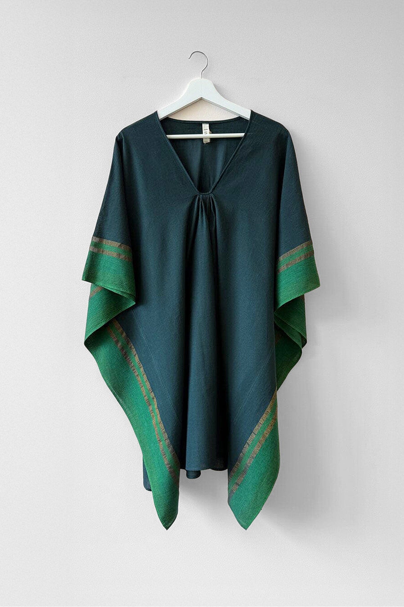 Green tunic with green patterned trim on a white hanger against a white background