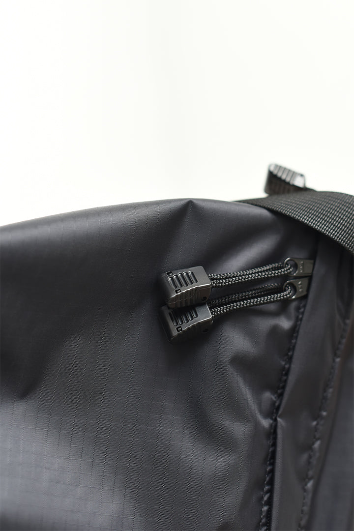 The zipper detailing of a black nylon crossbody bag for everyday wear