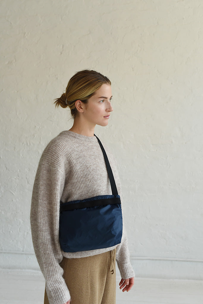 A woman wearing a navy nylon crossbody bag in navy and black
