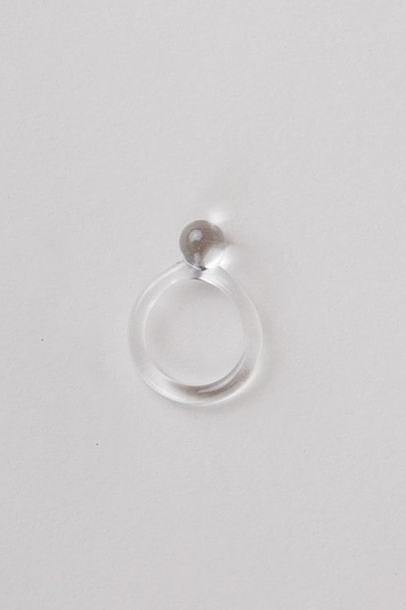 The top view of a clear handmade pyrex glass ring with a clear band and a small clear orb ball.