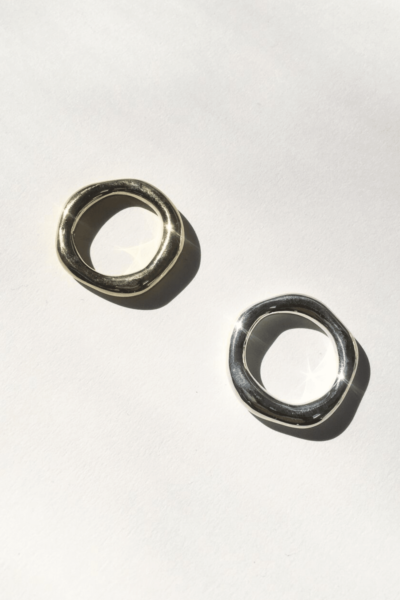 Two sterling silver organic bands on a white background