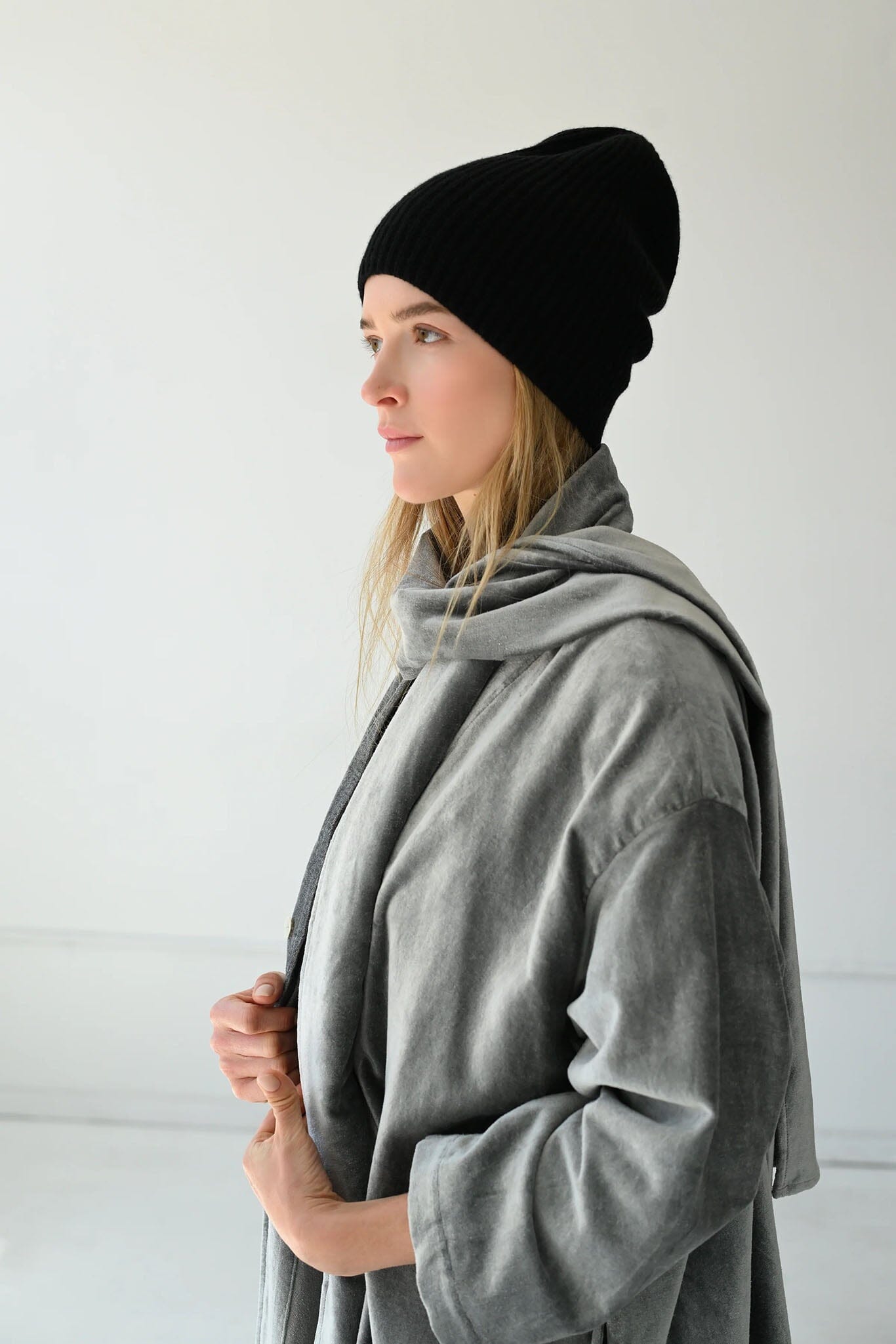 Woman wearing a black beanie and gray coat against a white background