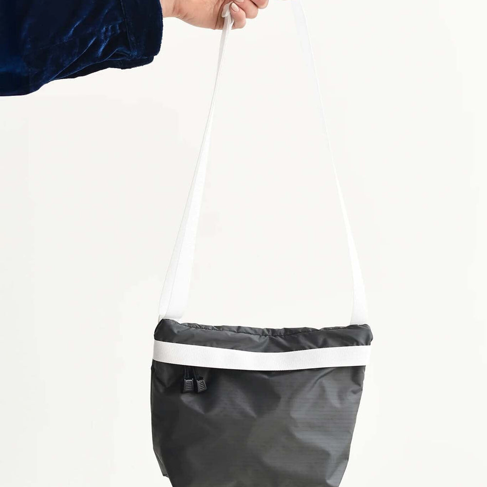 Person holding a black and white nylon zipper bag against a white background