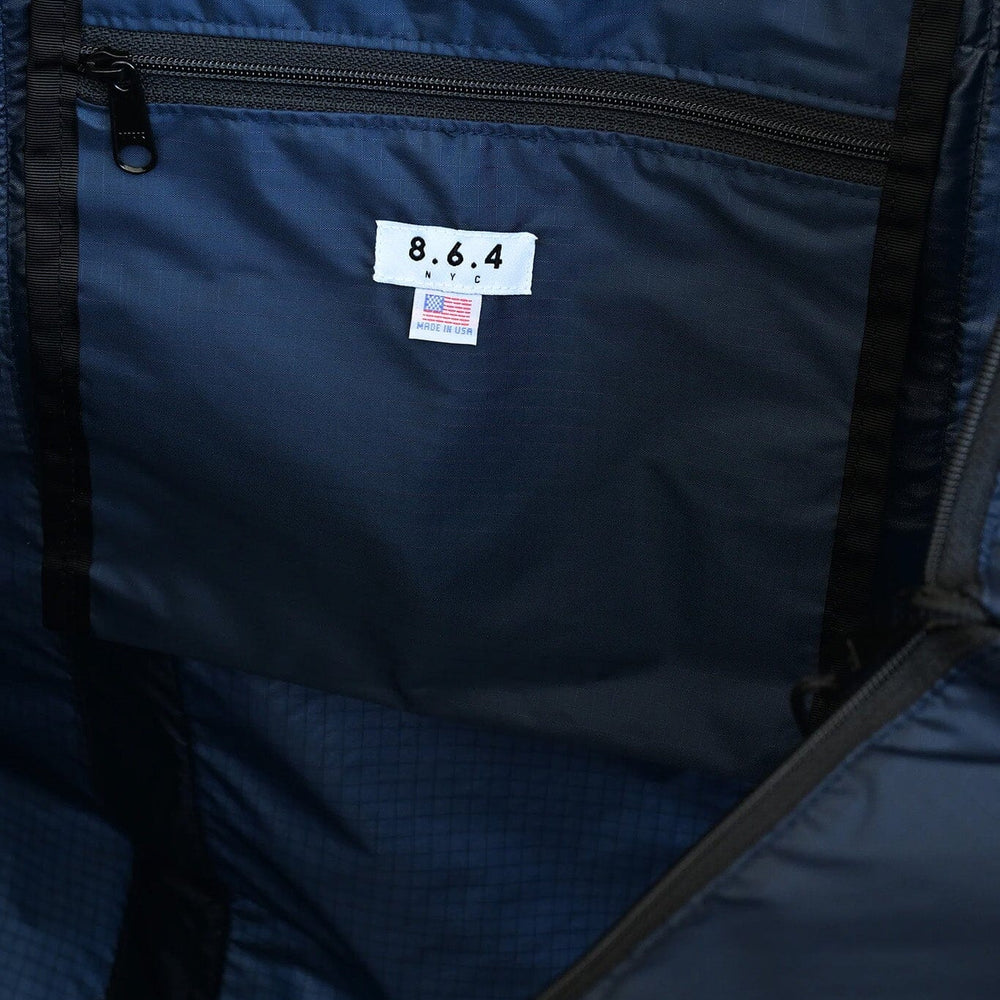 
                  
                    Close-up of a blue nylon tote bag with a label showing the brand 8.6.4.
                  
                