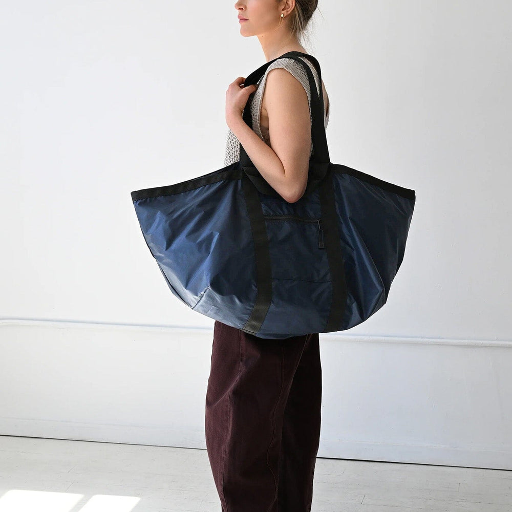 Woman holding a large blue tote bag against a white background