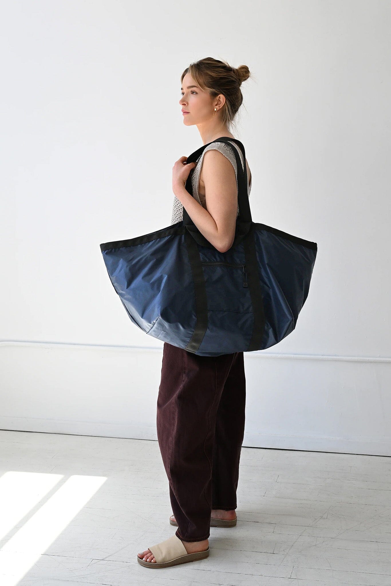 Woman holding a large blue tote bag against a white background