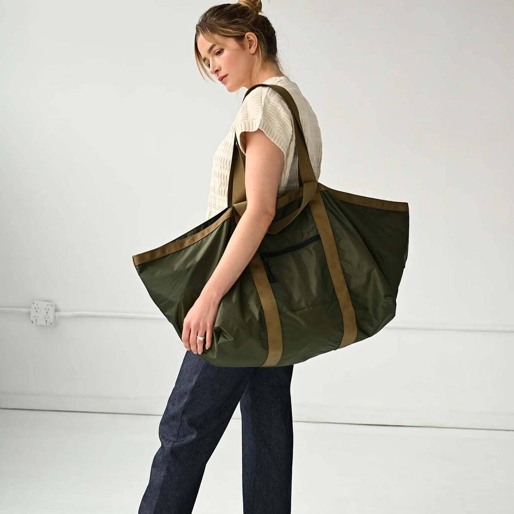 Woman carrying a large green and brown tote bag on a white background