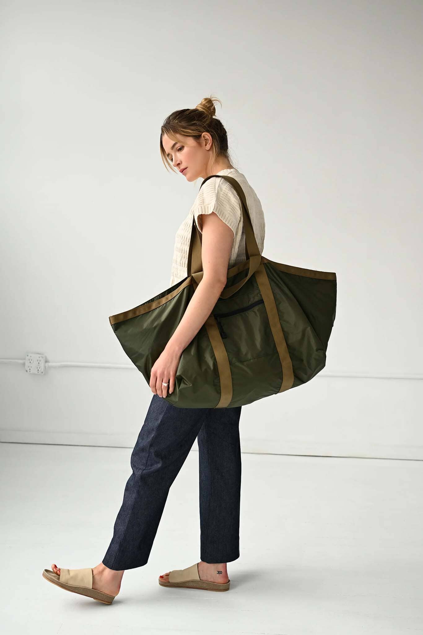 Woman carrying a large green and brown tote bag on a white background