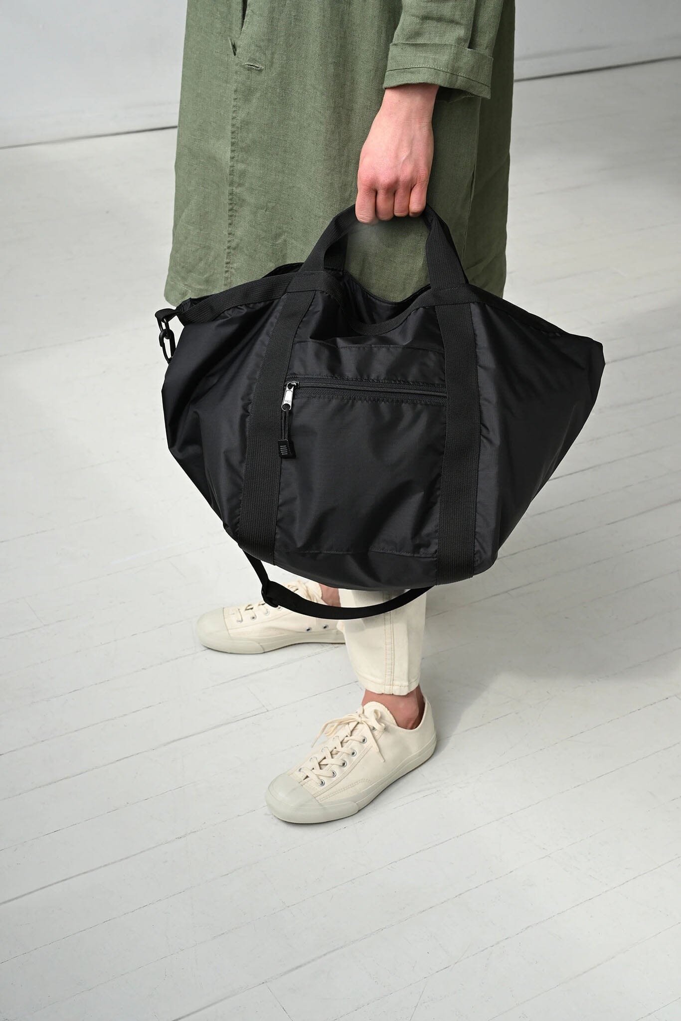 Person holding a black bag on a light gray floor