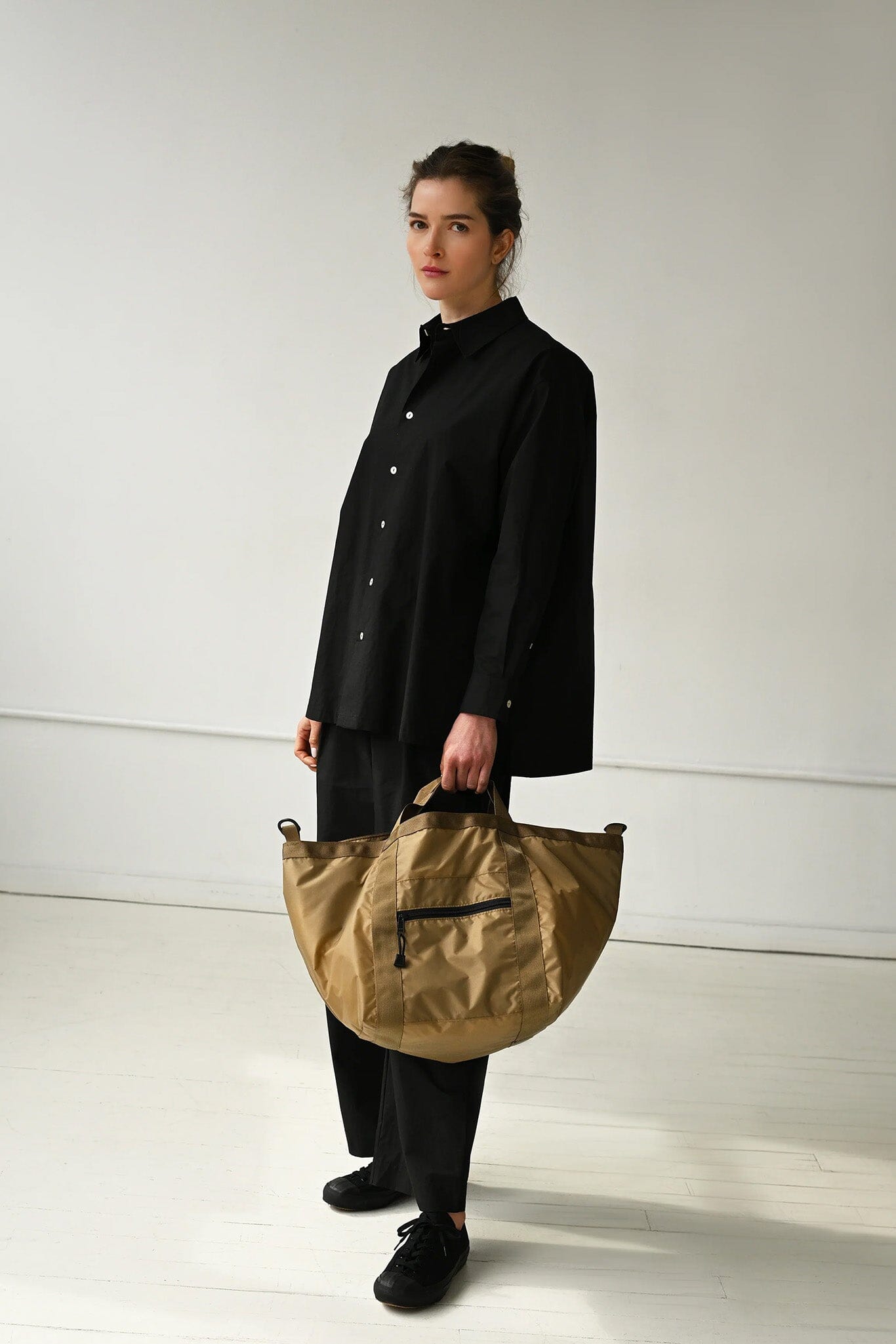 Person holding a beige bag against a white background