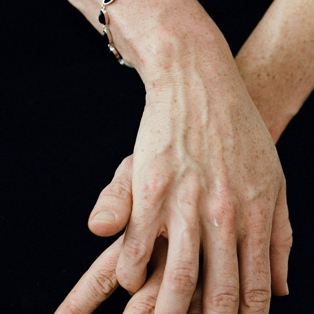 Close-up of hands with a black beaded bracelet on a black background