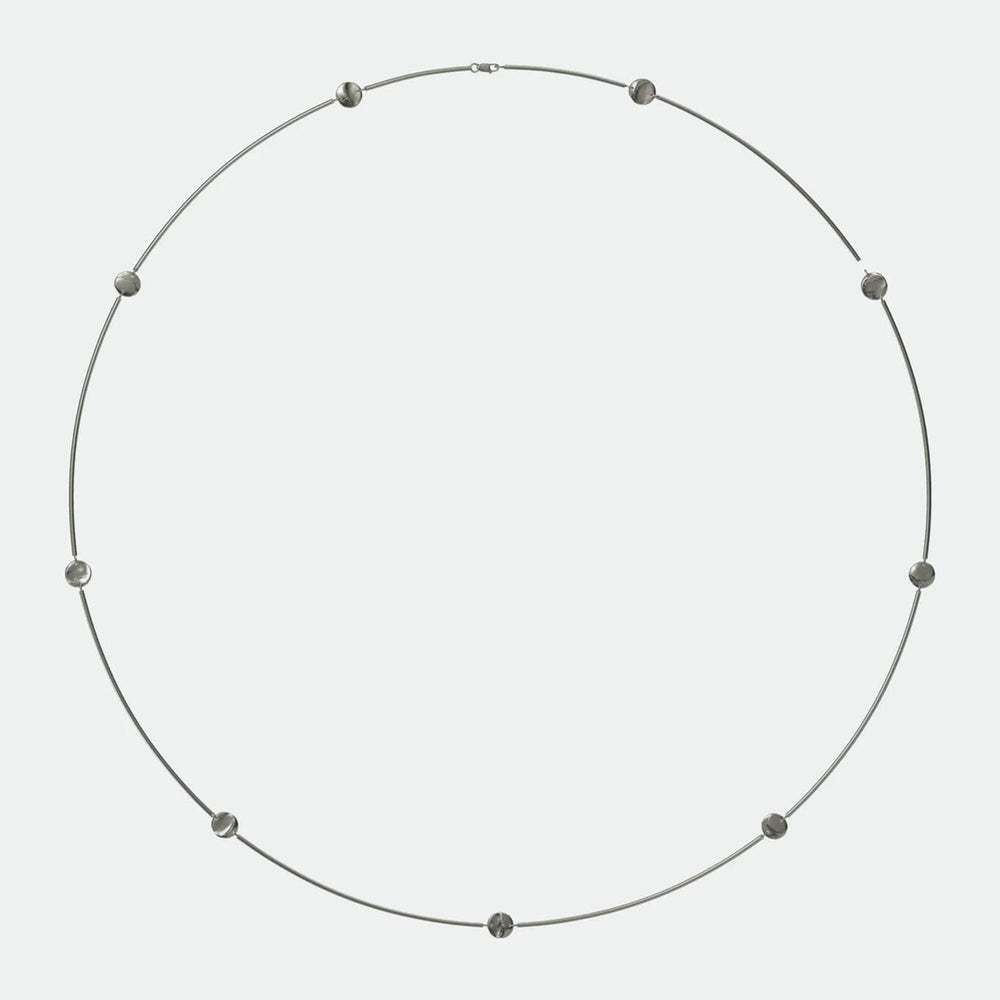 
                  
                    Necklace with small, flat coin beads on a light gray background
                  
                