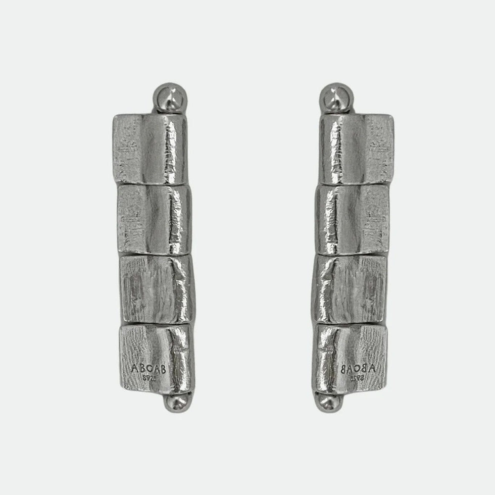 Pair of silver cylindrical stud earrings on a white background