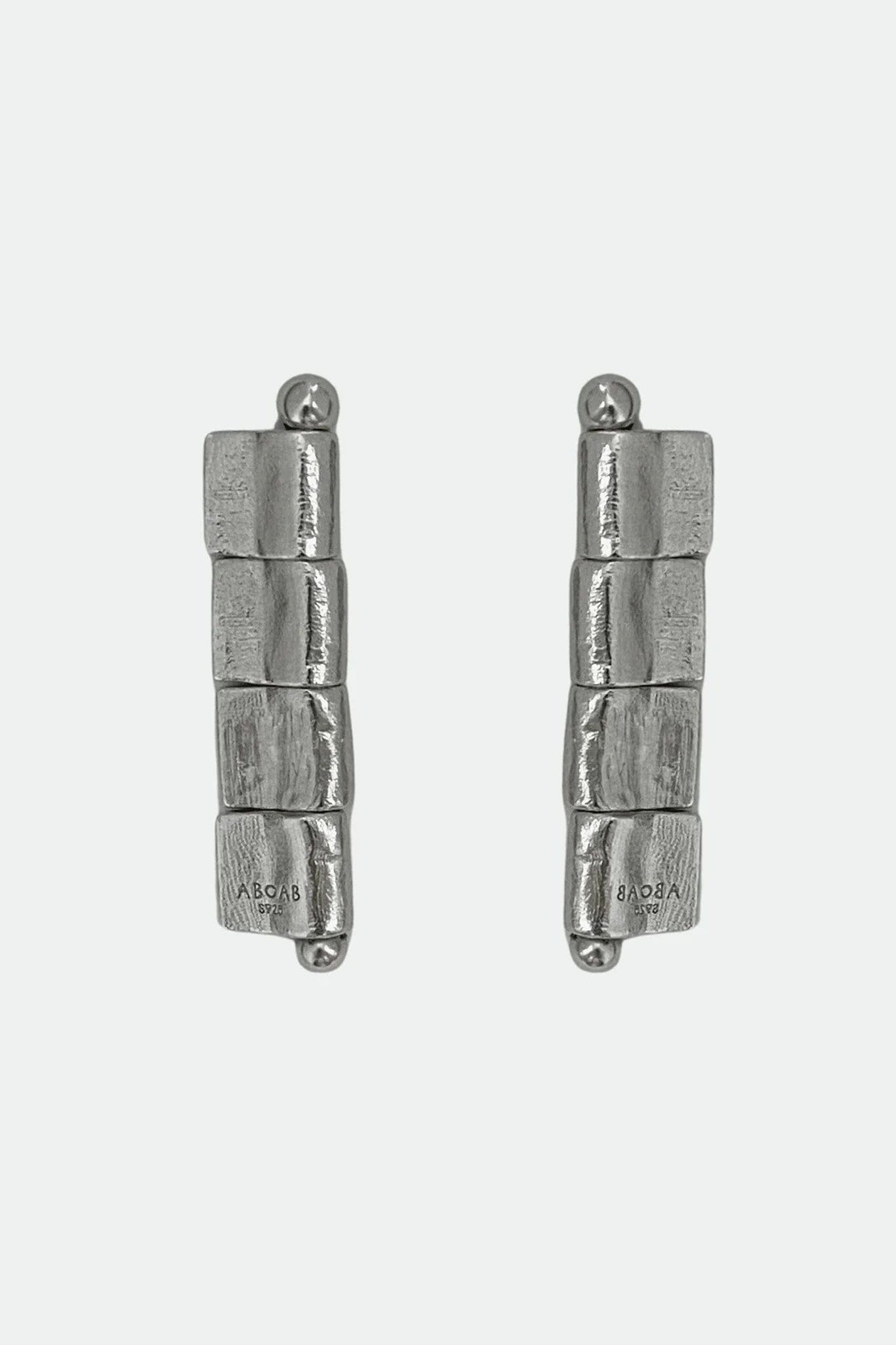 Pair of silver cylindrical stud earrings on a white background