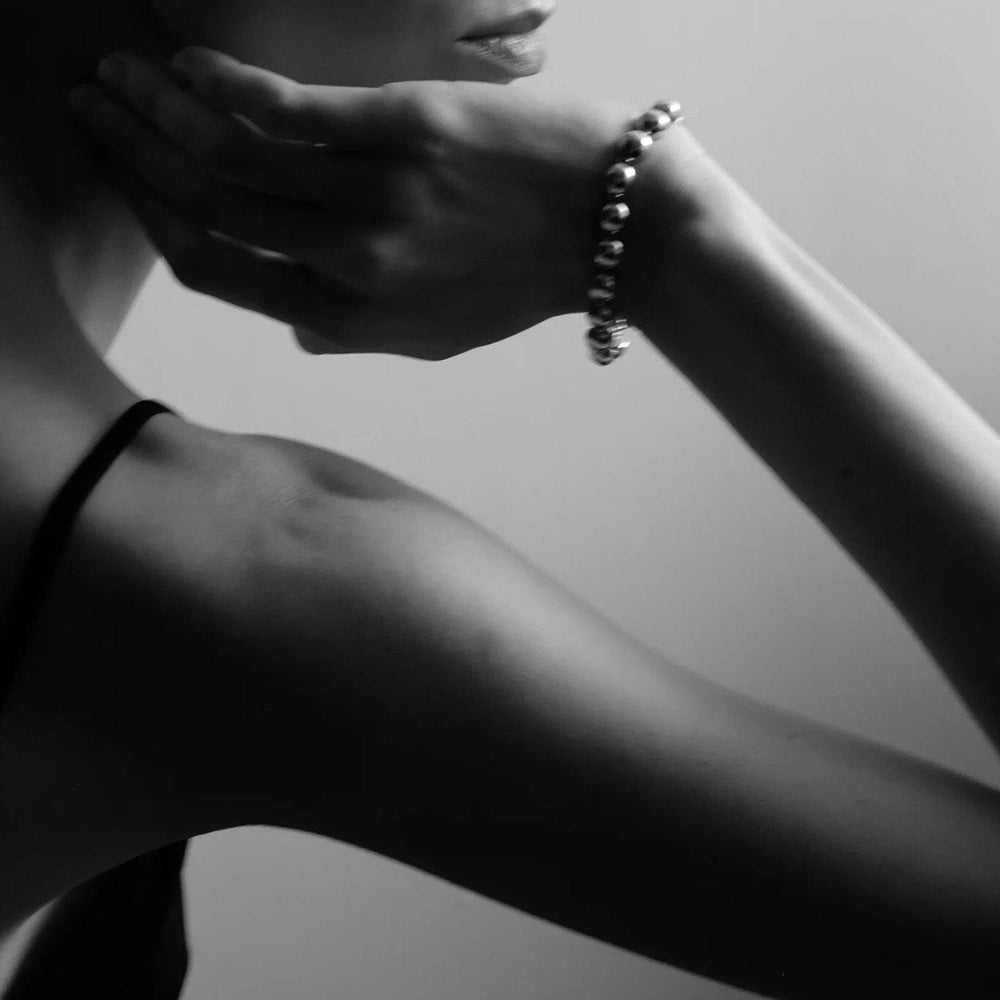 
                  
                    Black and white portrait of a woman with a silver dome bracelet
                  
                